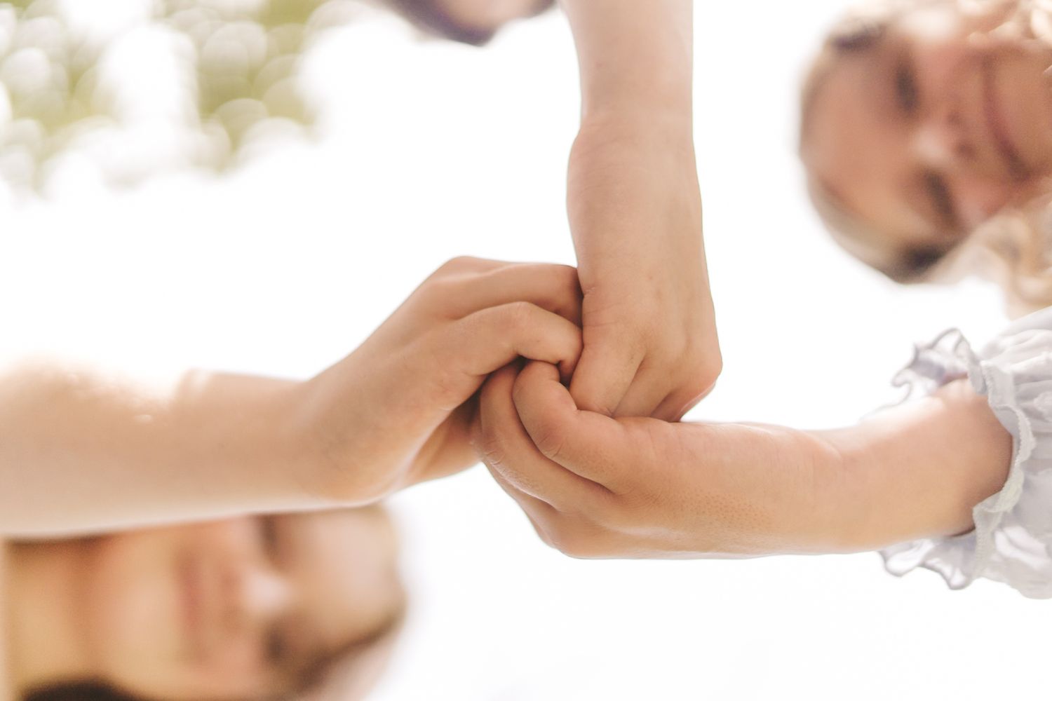 Group of people joining hands together in a circle, symbolizing teamwork, unity, and collaboration outdoors.