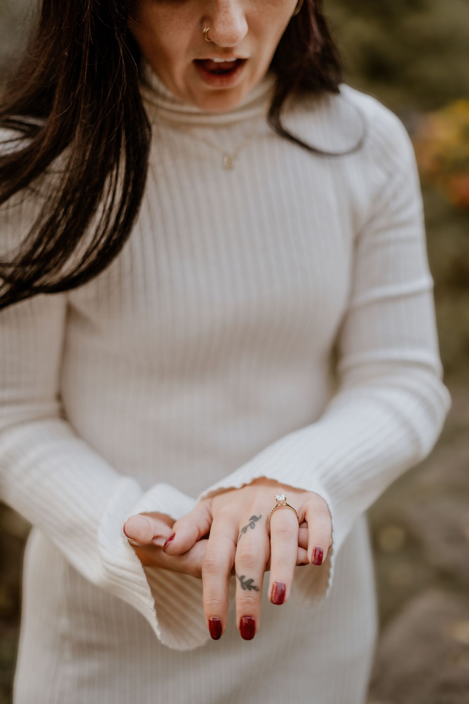 Detail shots of hands showing off a new engagement ring with red manicured nails.