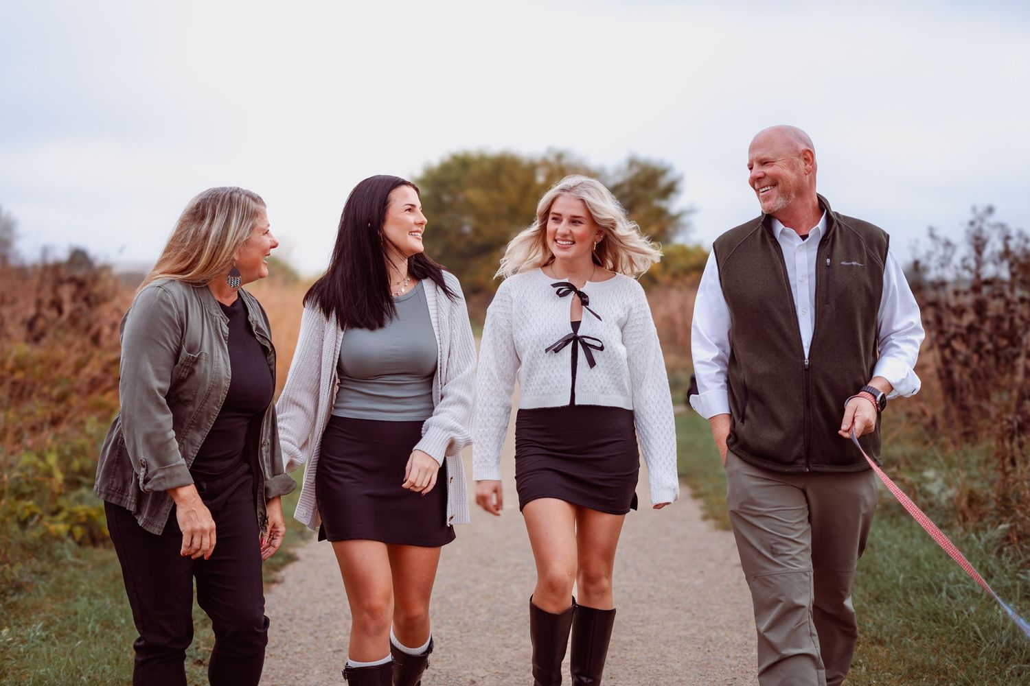 Group walking together on path through autumn field wearing casual attire.