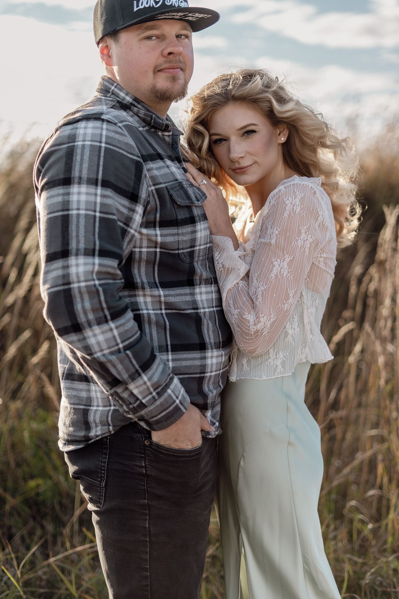 A tender moment between a couple in plaid and lace against a field of wheat.