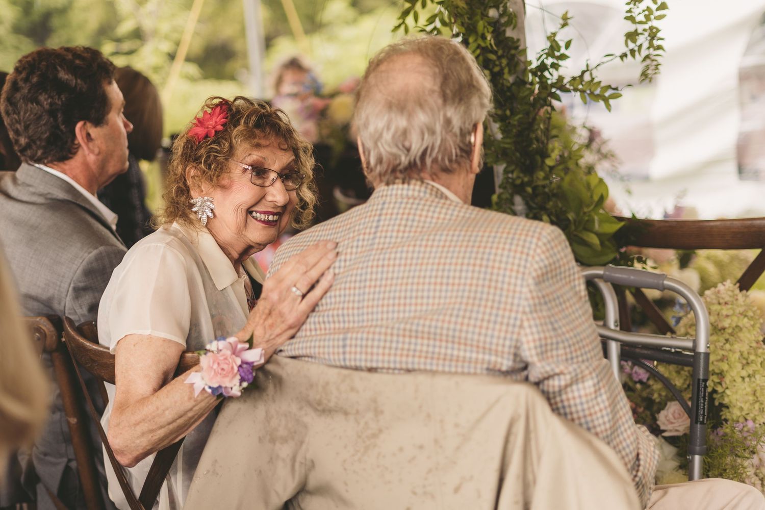 Elderly couple sharing a joyful moment at a wedding reception under a decorated tent.