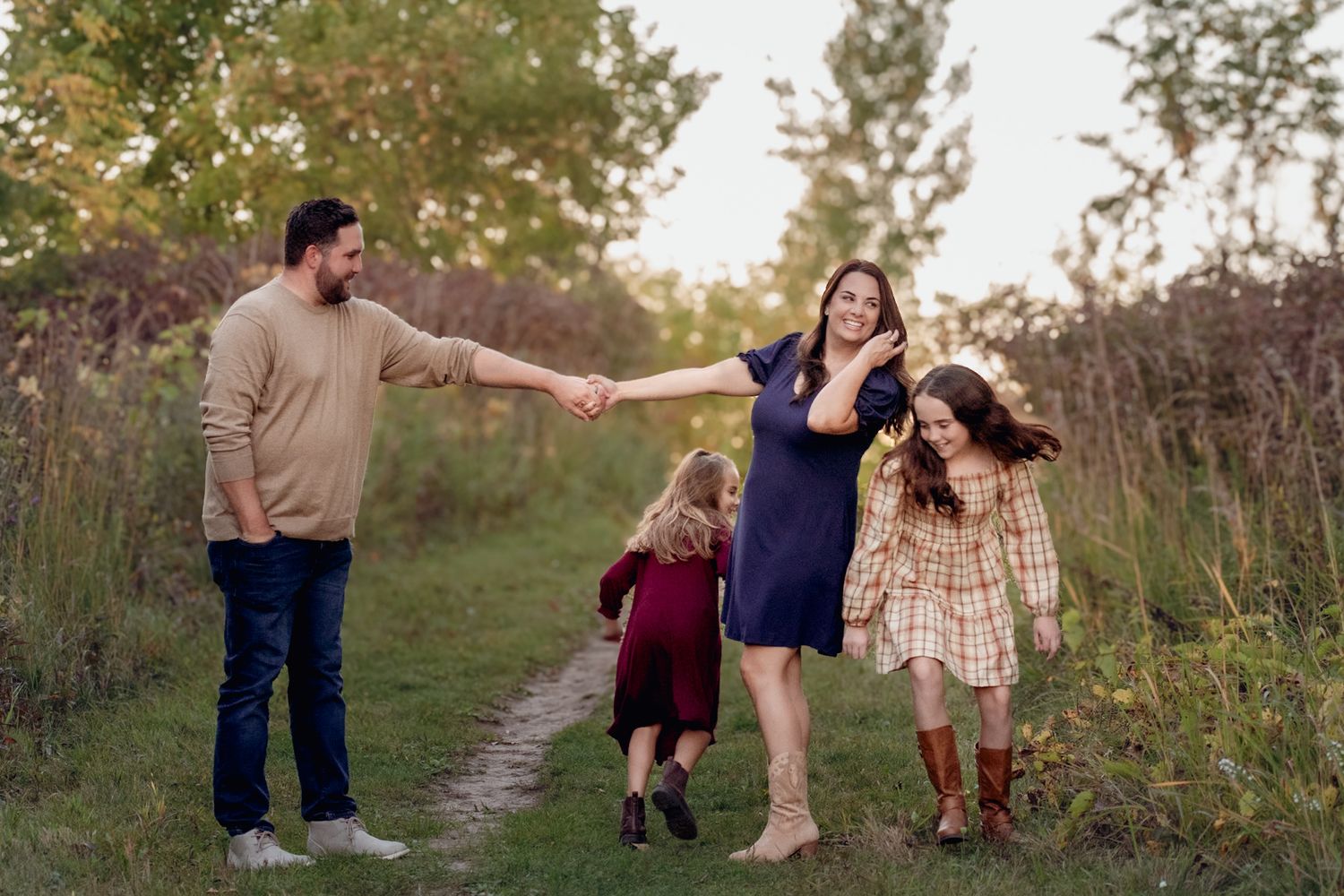 Family walking together on a nature trail during golden hour.