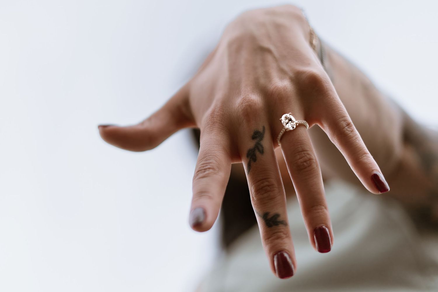 Close-up shots of hands displaying an engagement ring against a white background.