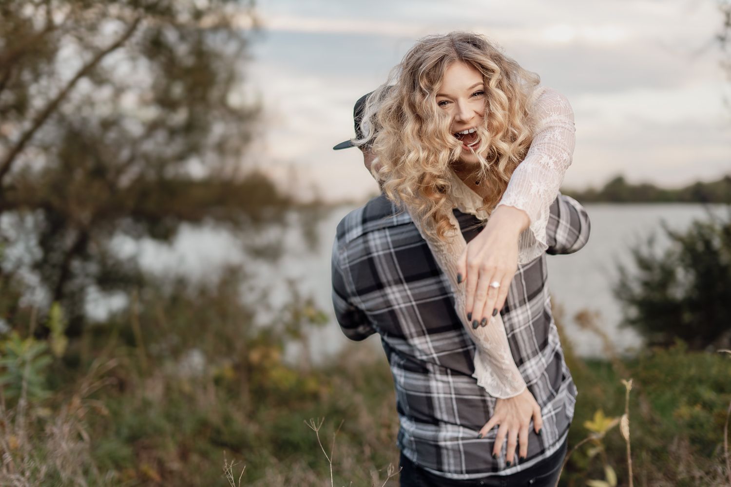 A couple shares playful moments along a nature path during golden hour.