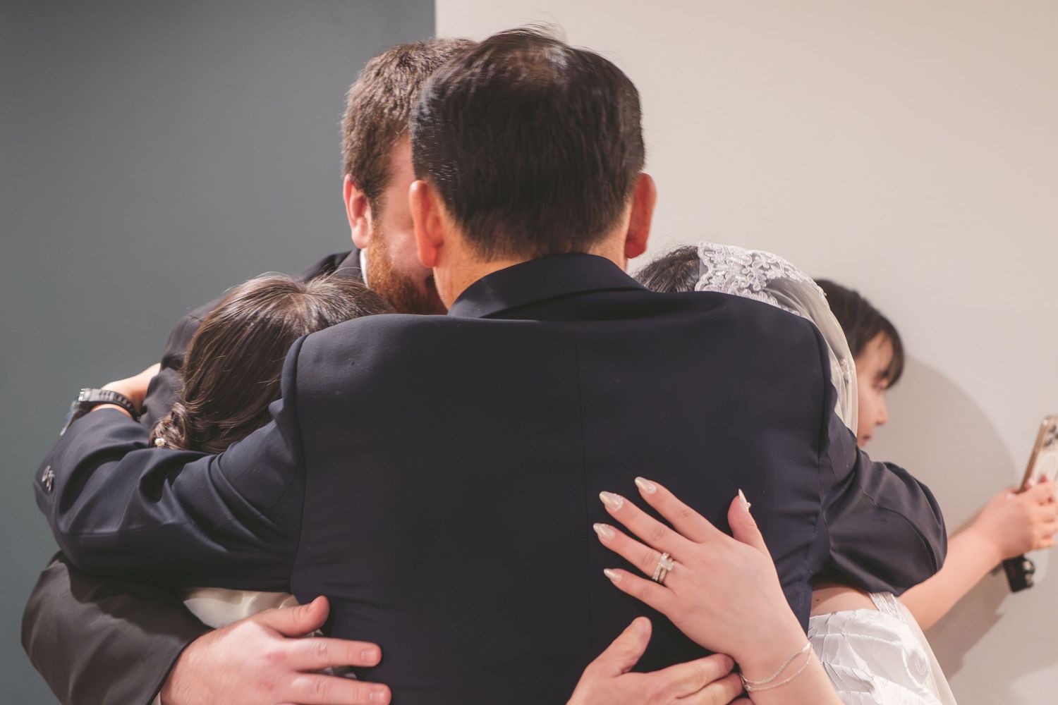 Group of people sharing a warm embrace in a heartfelt group hug at a formal gathering.