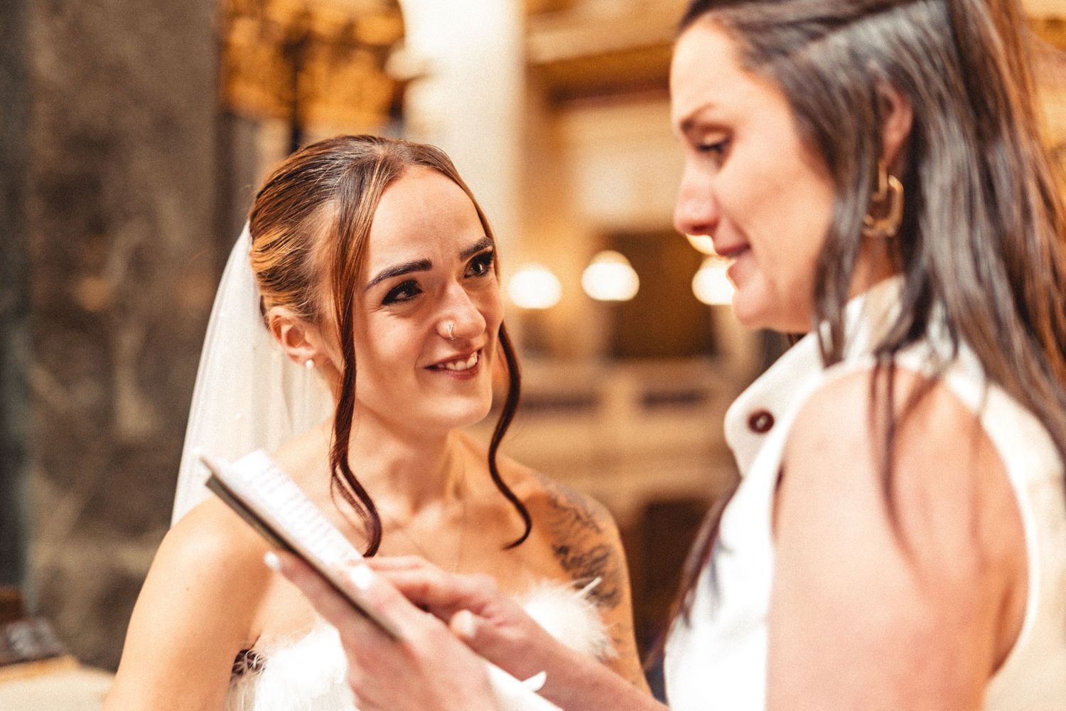 Two women share a joyful moment together during an intimate conversation in warm lighting.