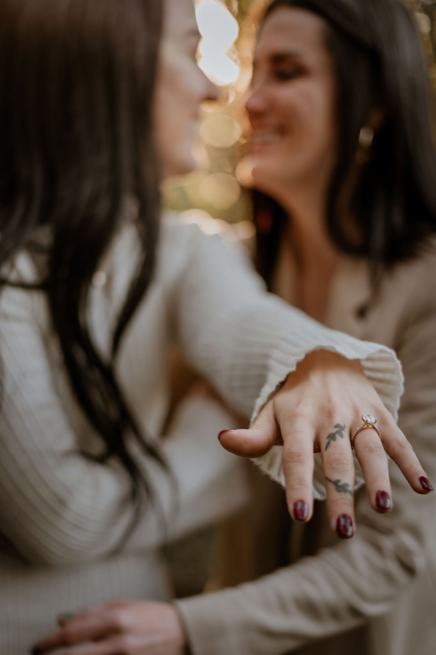 Close-up shots of hands displaying an engagement ring with burgundy nail polish.