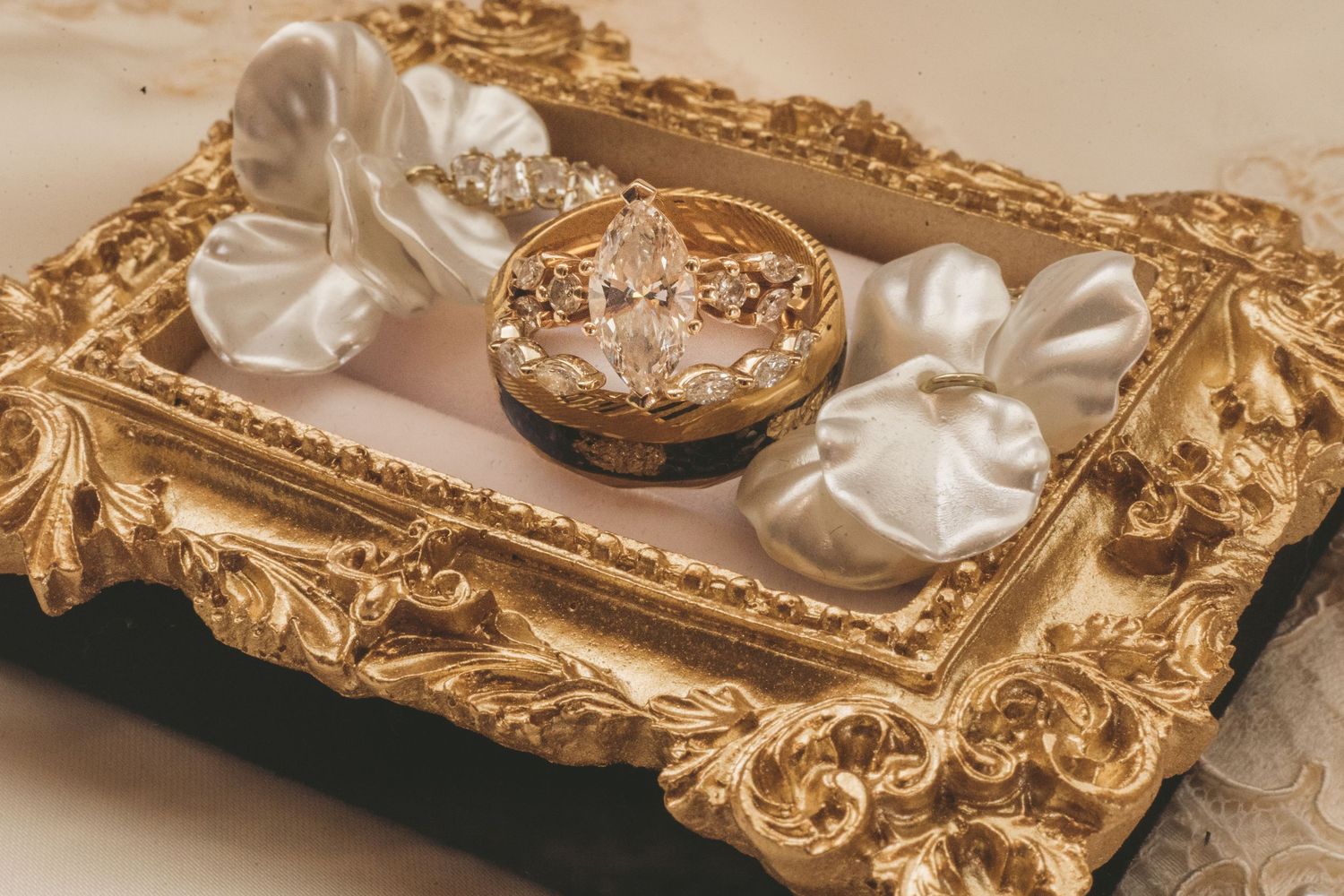 Elegant gold ornate tray with diamond crown ring in jewel box and white satin ribbon bows for wedding.