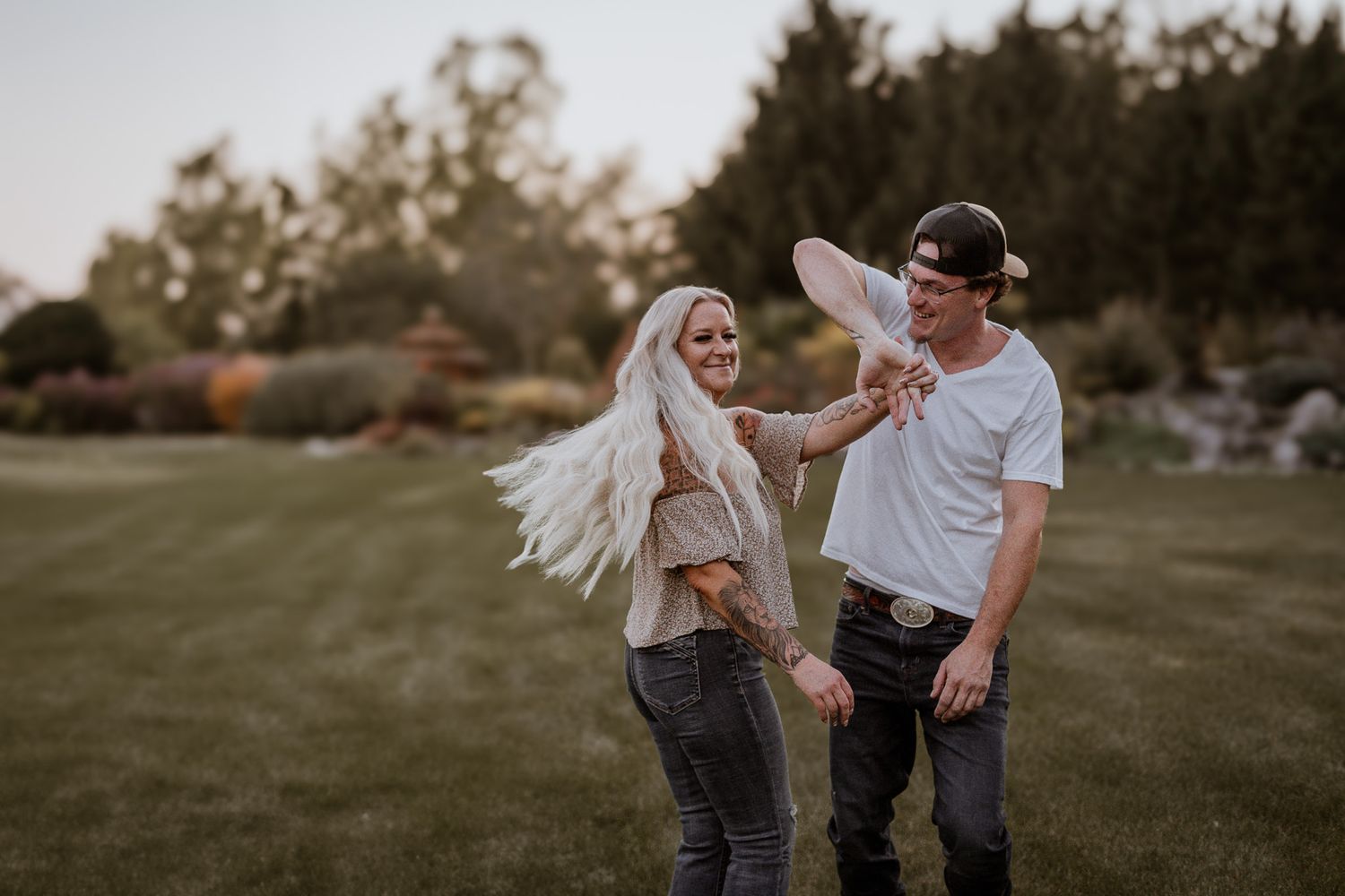 Two people playfully interact in a grassy field during golden hour.