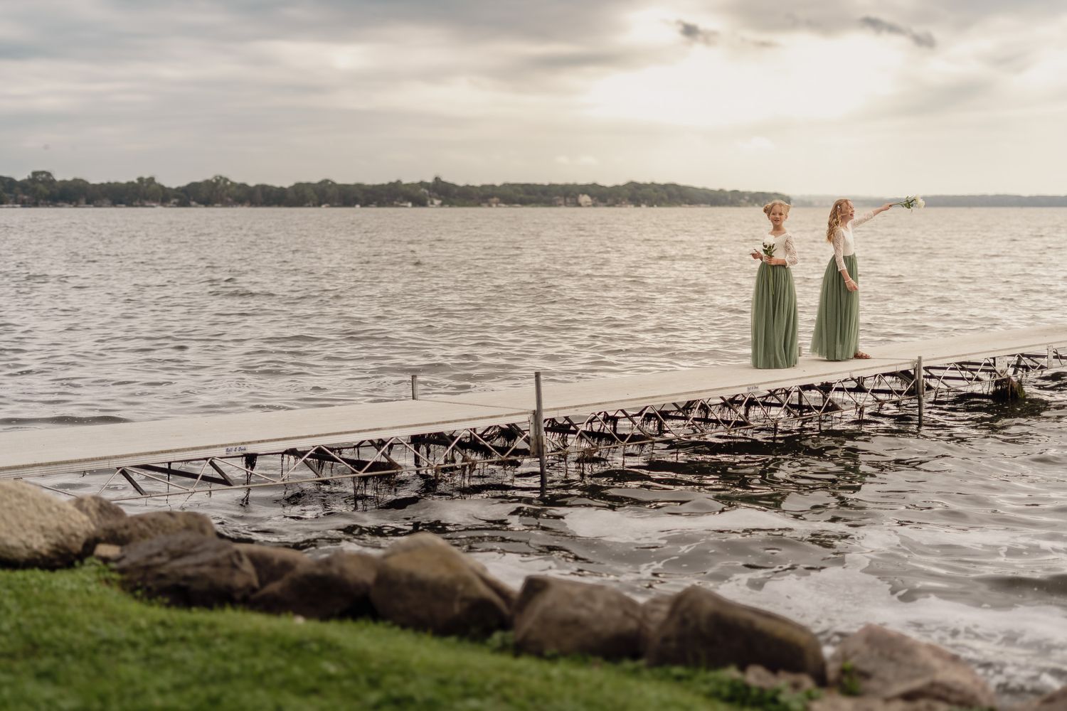 Scenic waterfront landscape with wooden dock stretching into calm waters at sunset.