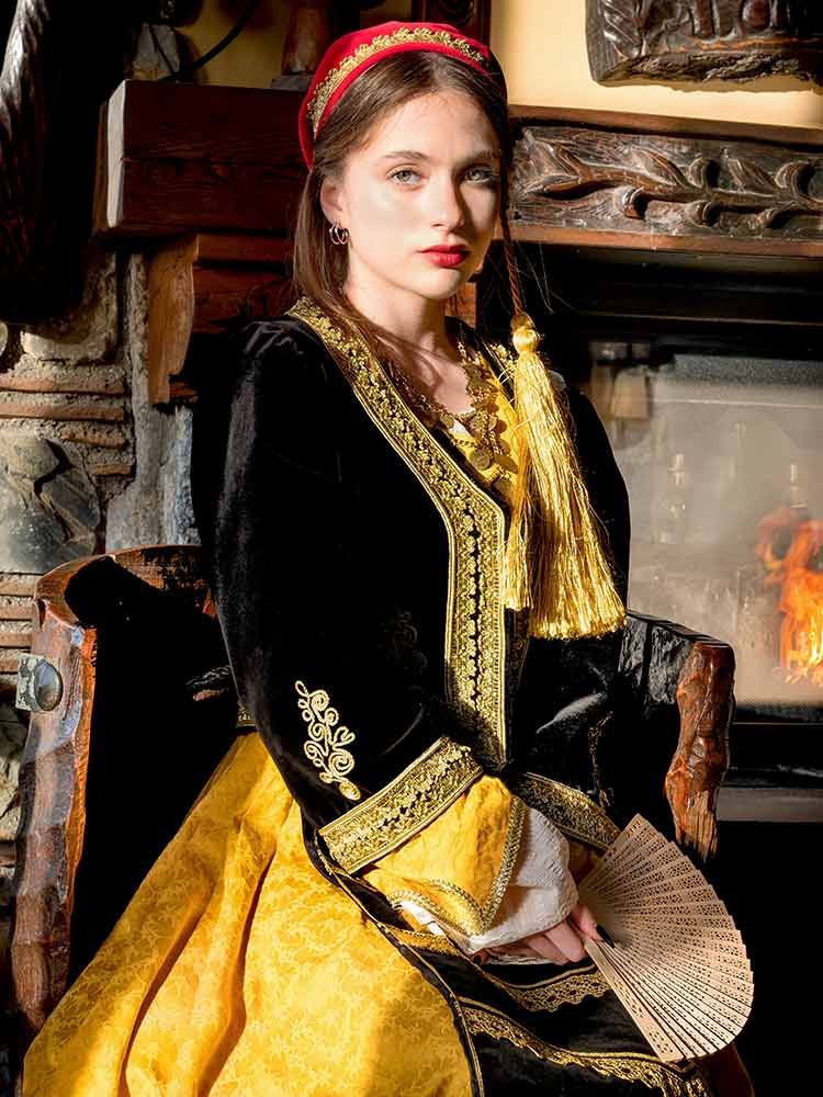 Kleurportret van een vrouw in traditionele kledij, binnenshuis gefotografeerd met warm licht, met nadruk op textuur, vakmanschap en cultuur.