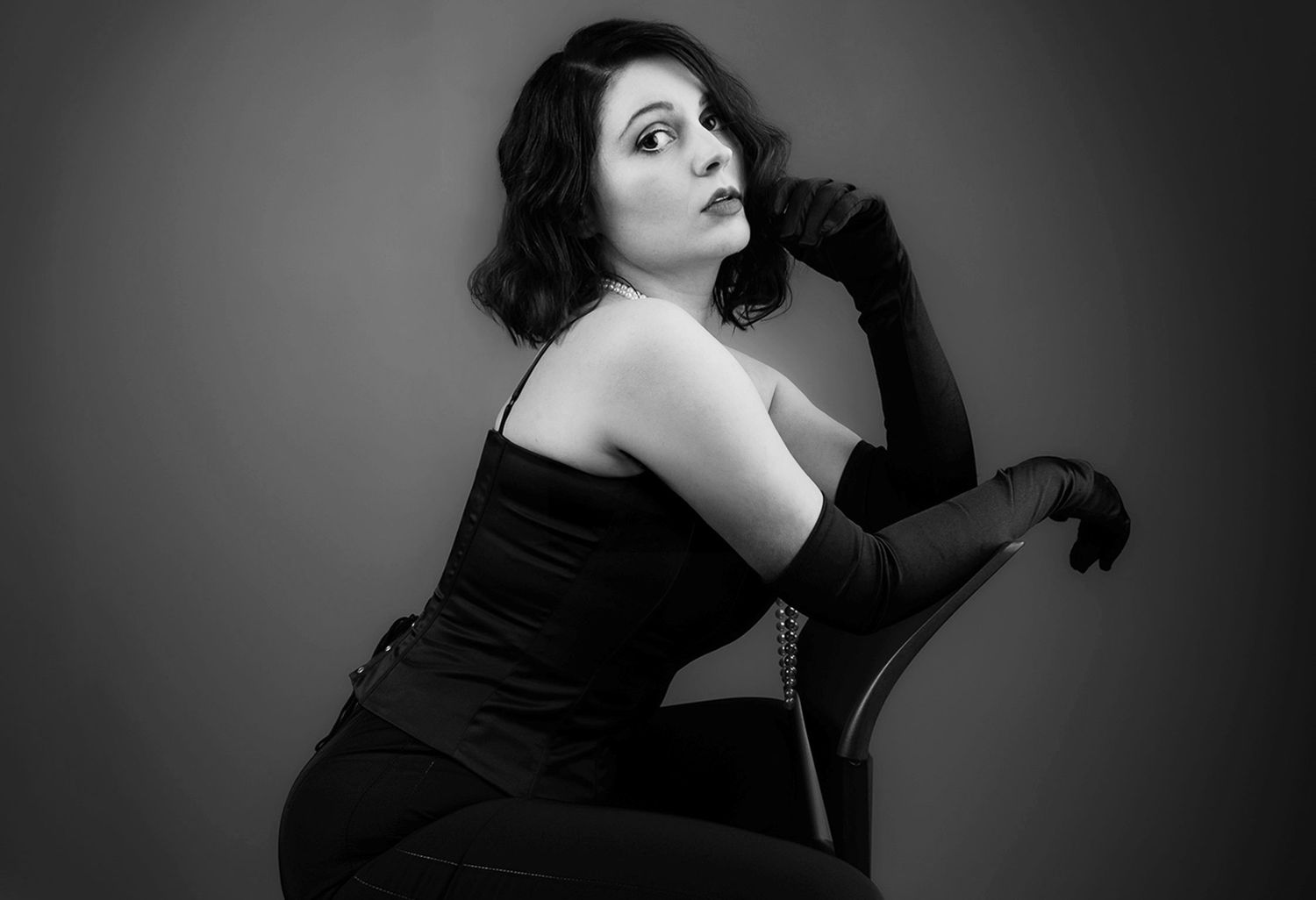 Zwart-wit studioportret van een vrouw, vastgelegd met een redactionele en expressieve pose.
