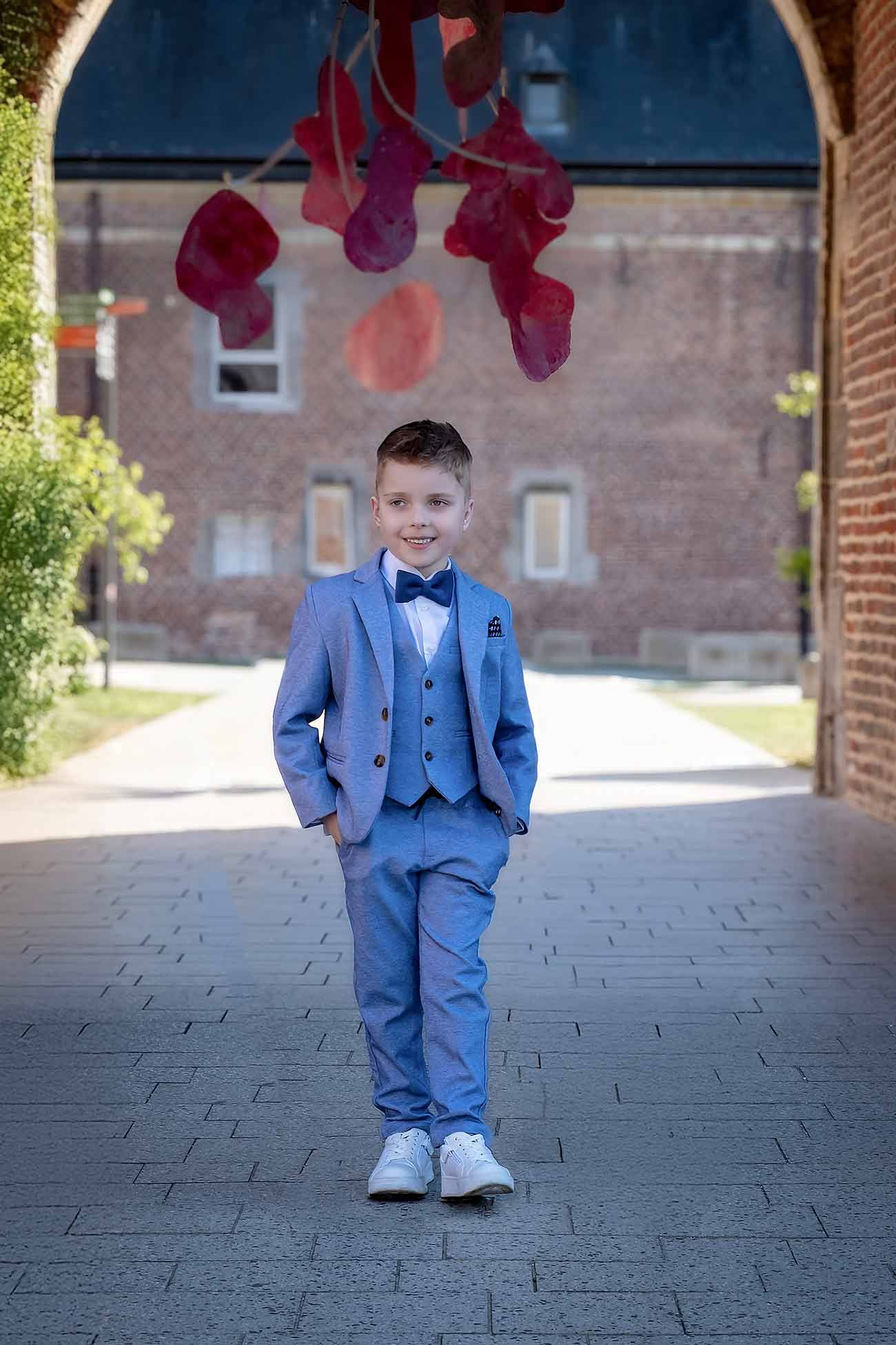 Eerste communieportret van een jonge jongen in een blauw pak, vastgelegd in natuurlijk licht door Maria Sia Photography in België.
