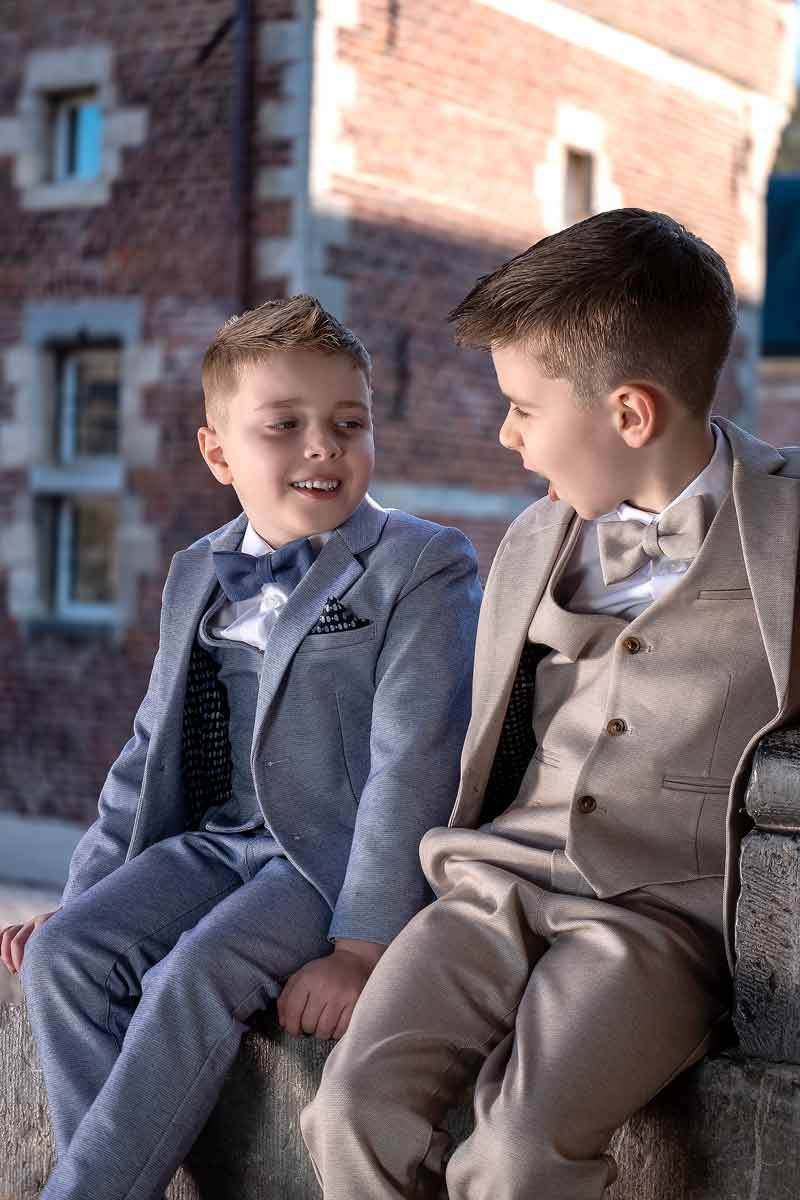 Communieportret van twee broers die samen buiten zitten, vastgelegd in natuurlijk licht met een spontaan familiemoment.