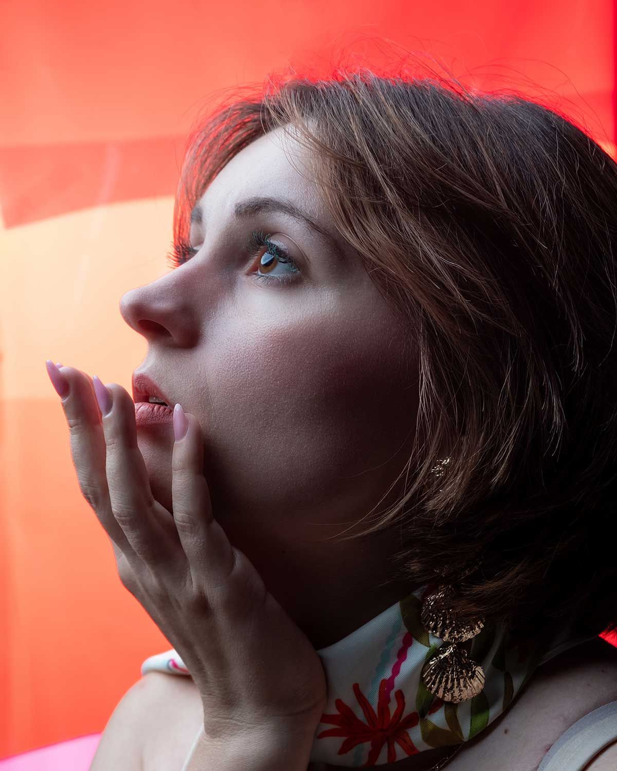 Studioportret van een vrouw met zacht licht en een expressieve houding, gefotografeerd in een redactionele stijl.