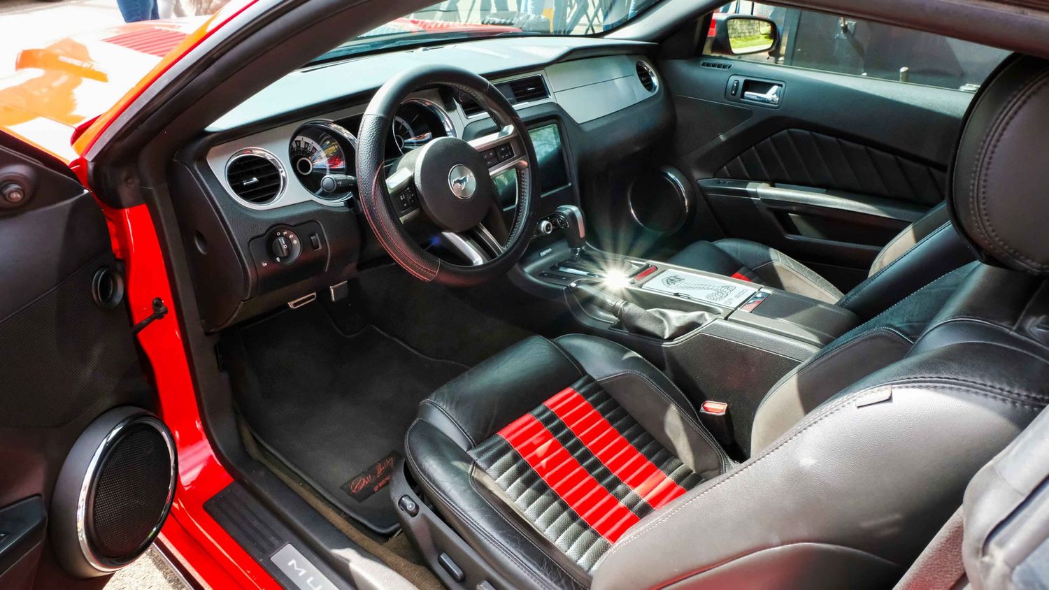Interieurzicht van een rode Ford Mustang, met focus op dashboard, stuurwiel en hoogwaardige materialen, gefotografeerd voor automotive brand
