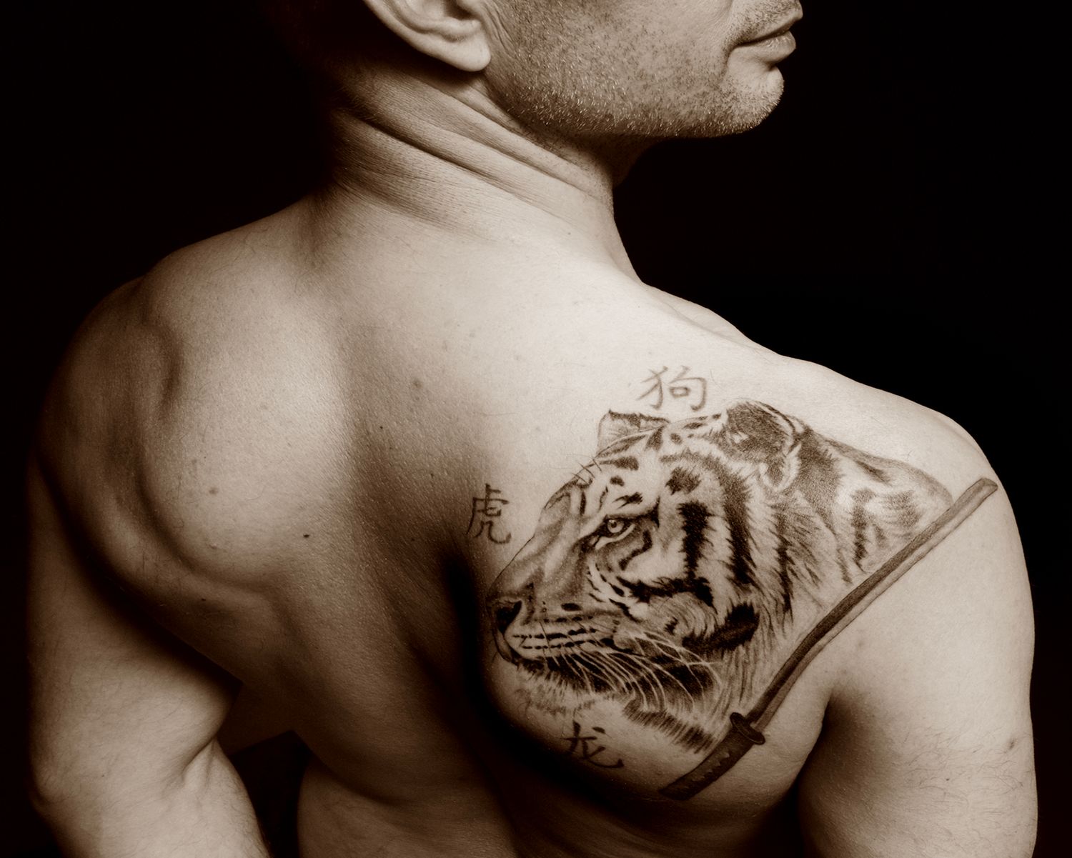 Artistiek close-up portret van een mannelijke rug met een gedetailleerde tijgertattoo, symbool voor kracht en identiteit.