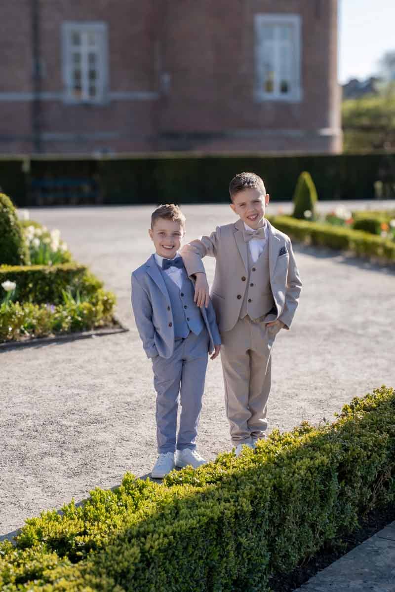 Communion and family photo of two boys walking together in a garden, natural light and storytelling style.