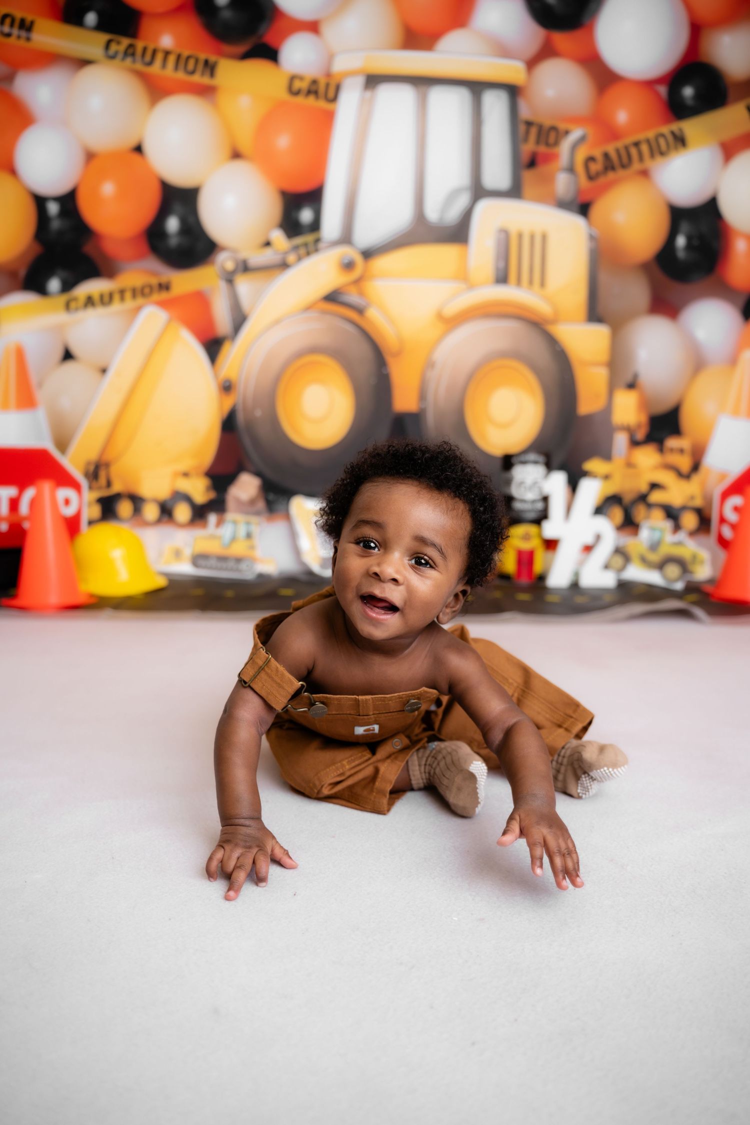 Metro Detroit children photographer Construction themed photo setup with orange and black balloons and toy bulldozer in background.