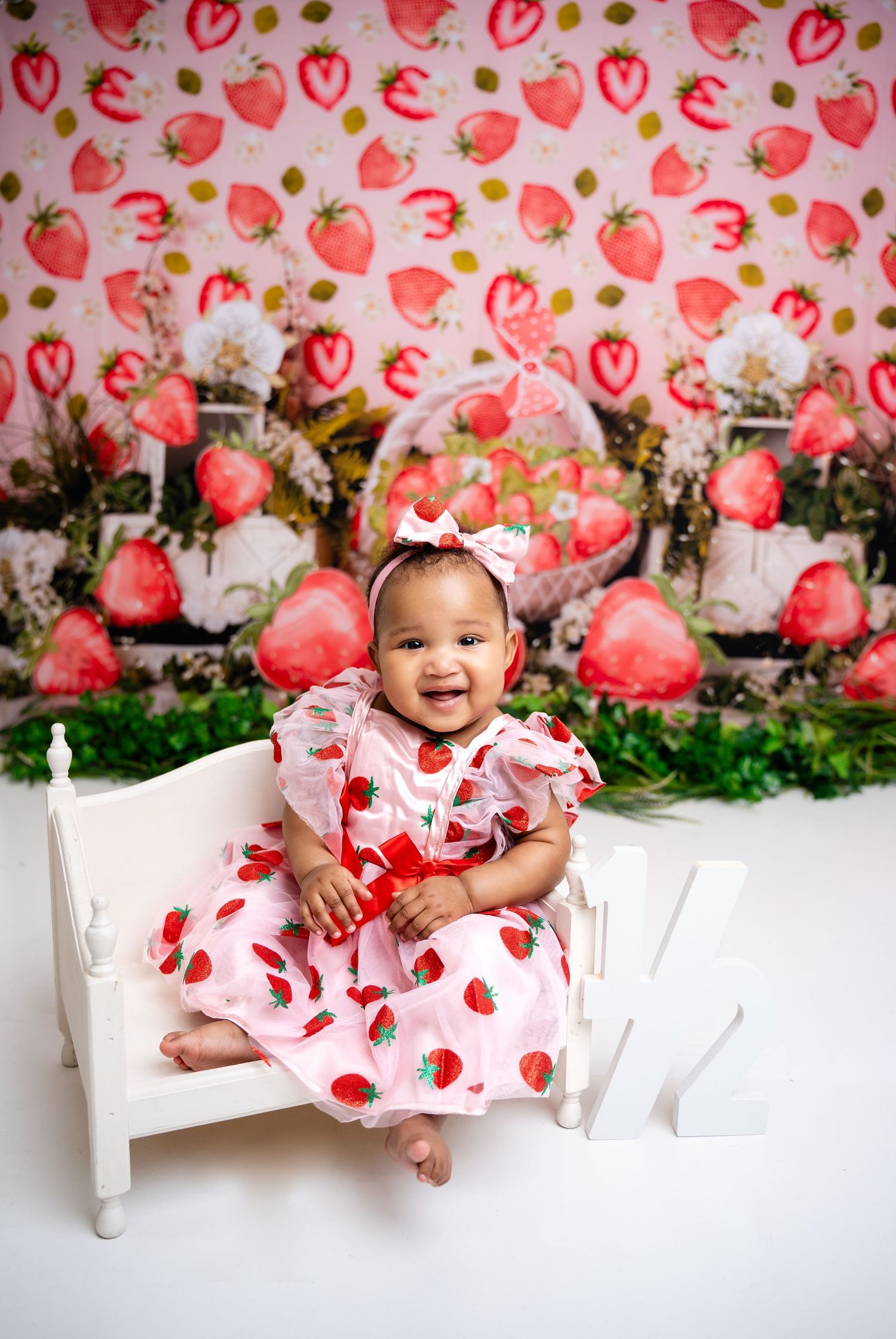 Metro Detroit children photographer Strawberry-themed photoshoot with white bench and pink floral dress.