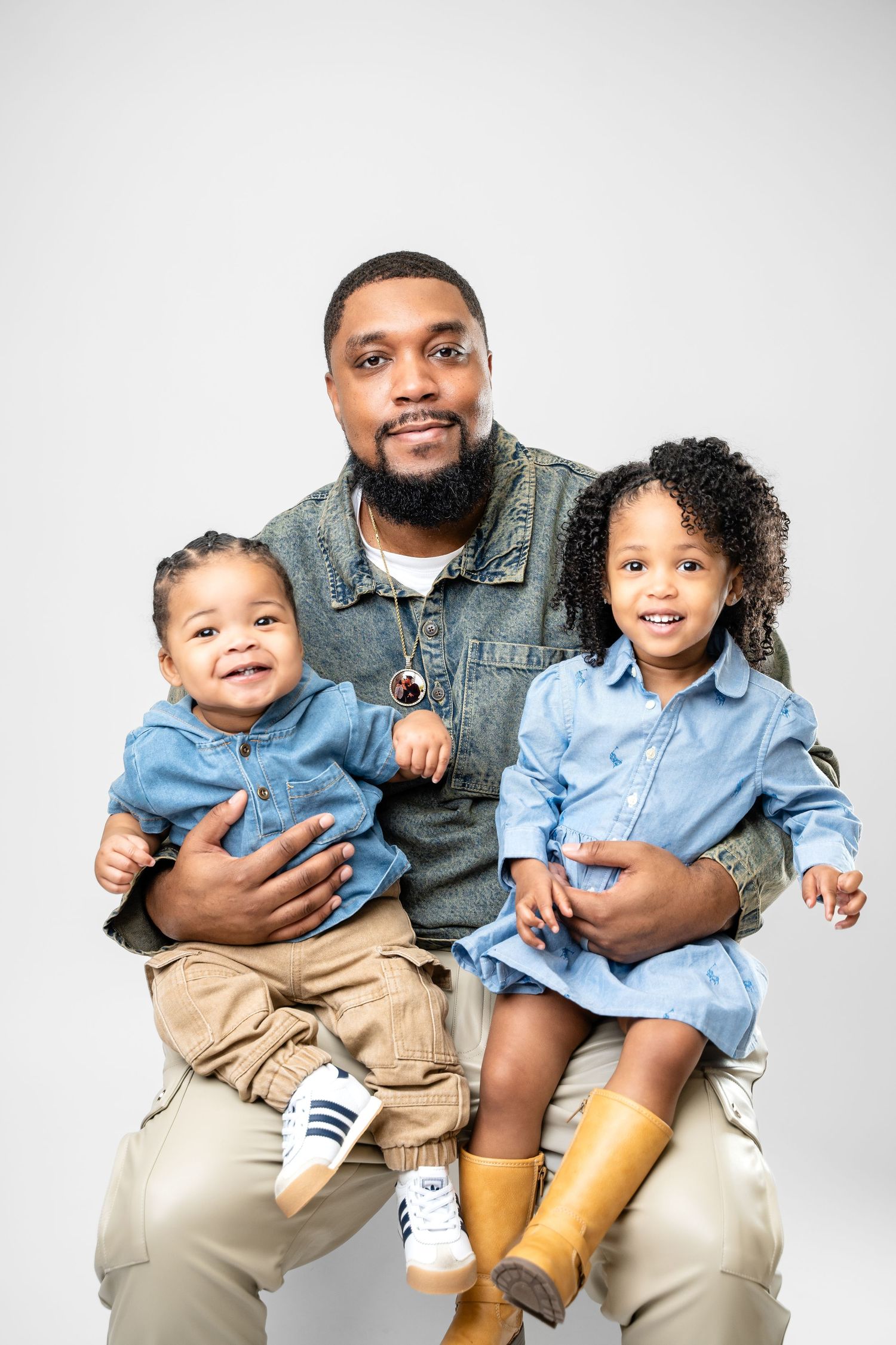Metro Detroit family photographer capturing a Family wearing coordinated denim and khaki outfits pose for studio portraits.