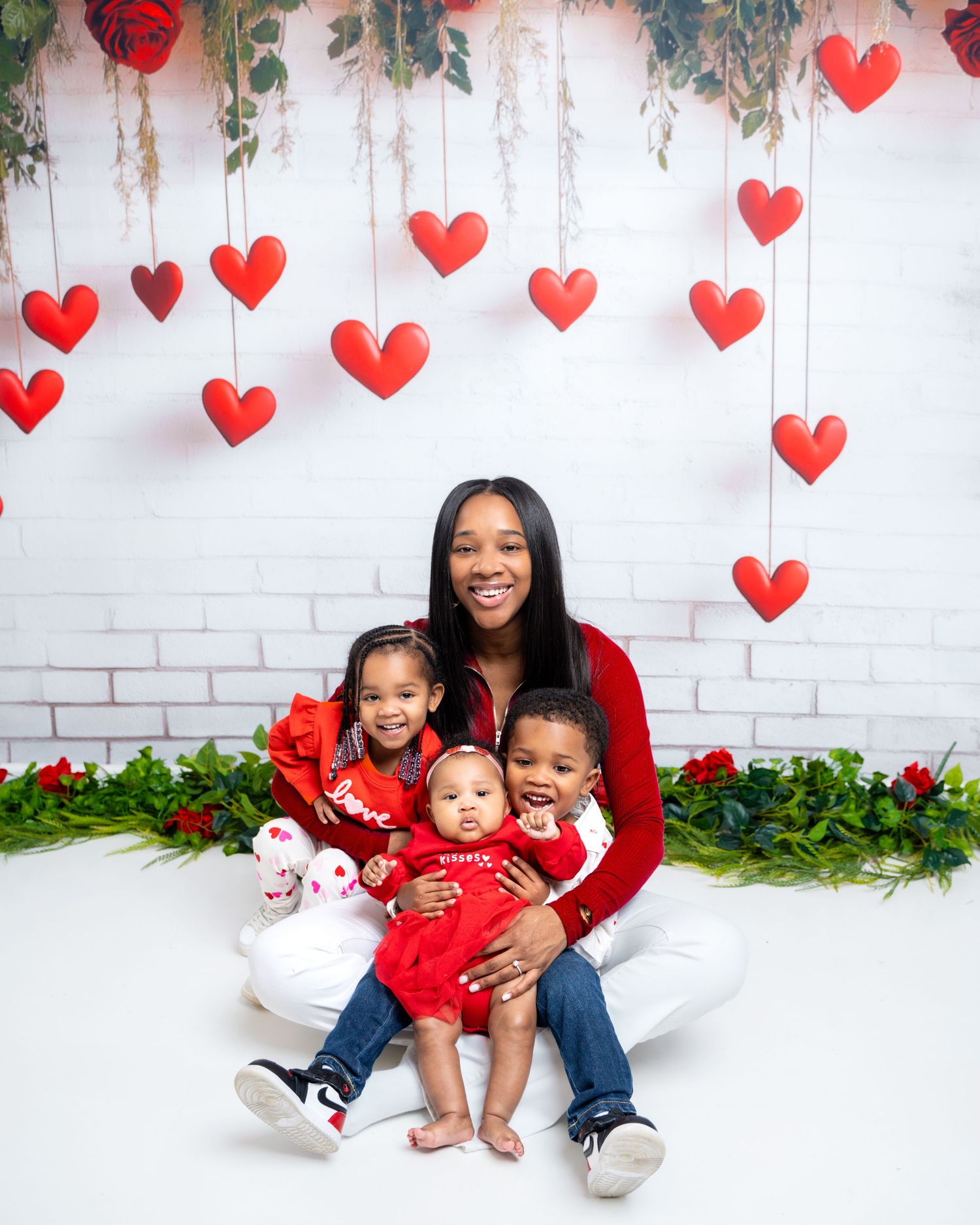 Metro Detroit family photographer capturing Family portrait session with red hearts and white brick wall