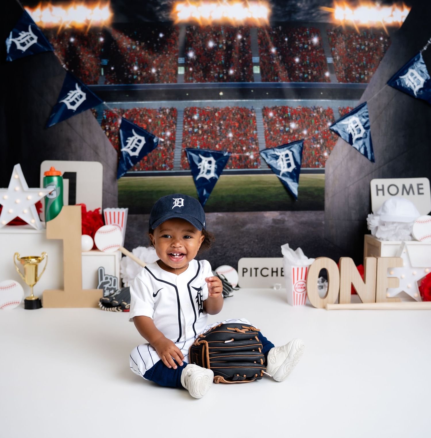 Metro Detroit children photographer Baseball stadium themed photo setup with Detroit Tigers decorations and sports equipment.