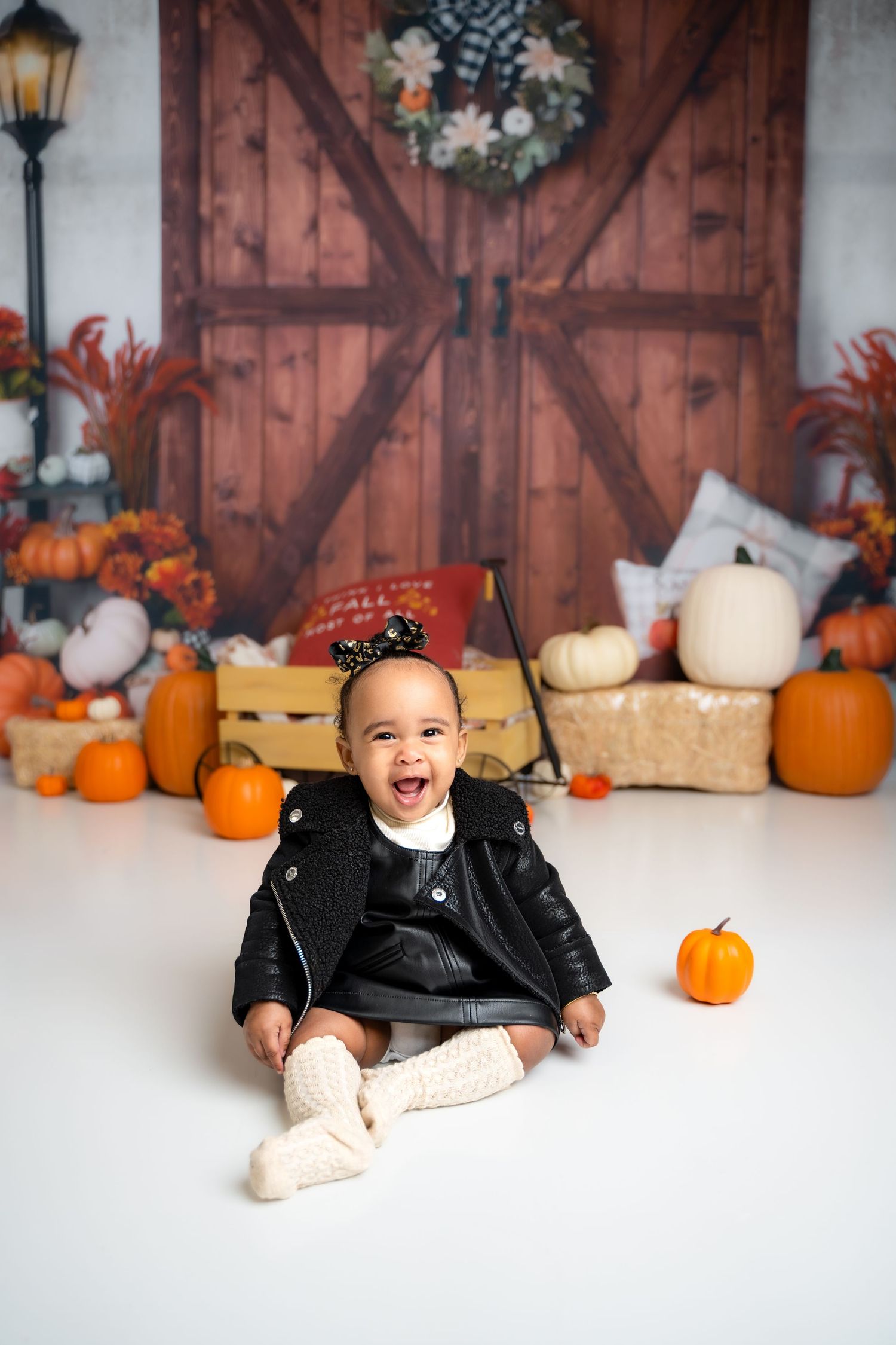 Metro Detroit children photographer photographing a toddler in studio Fall themed photo setup with pumpkins