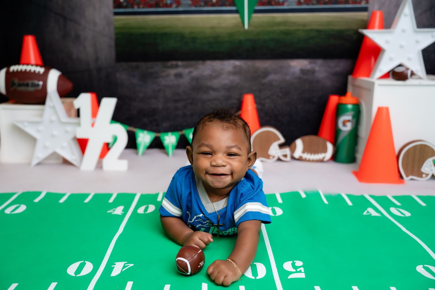 Metro Detroit children photographer A football-themed photo setup with green turf and decorative cones creates a sporty atmosphere.