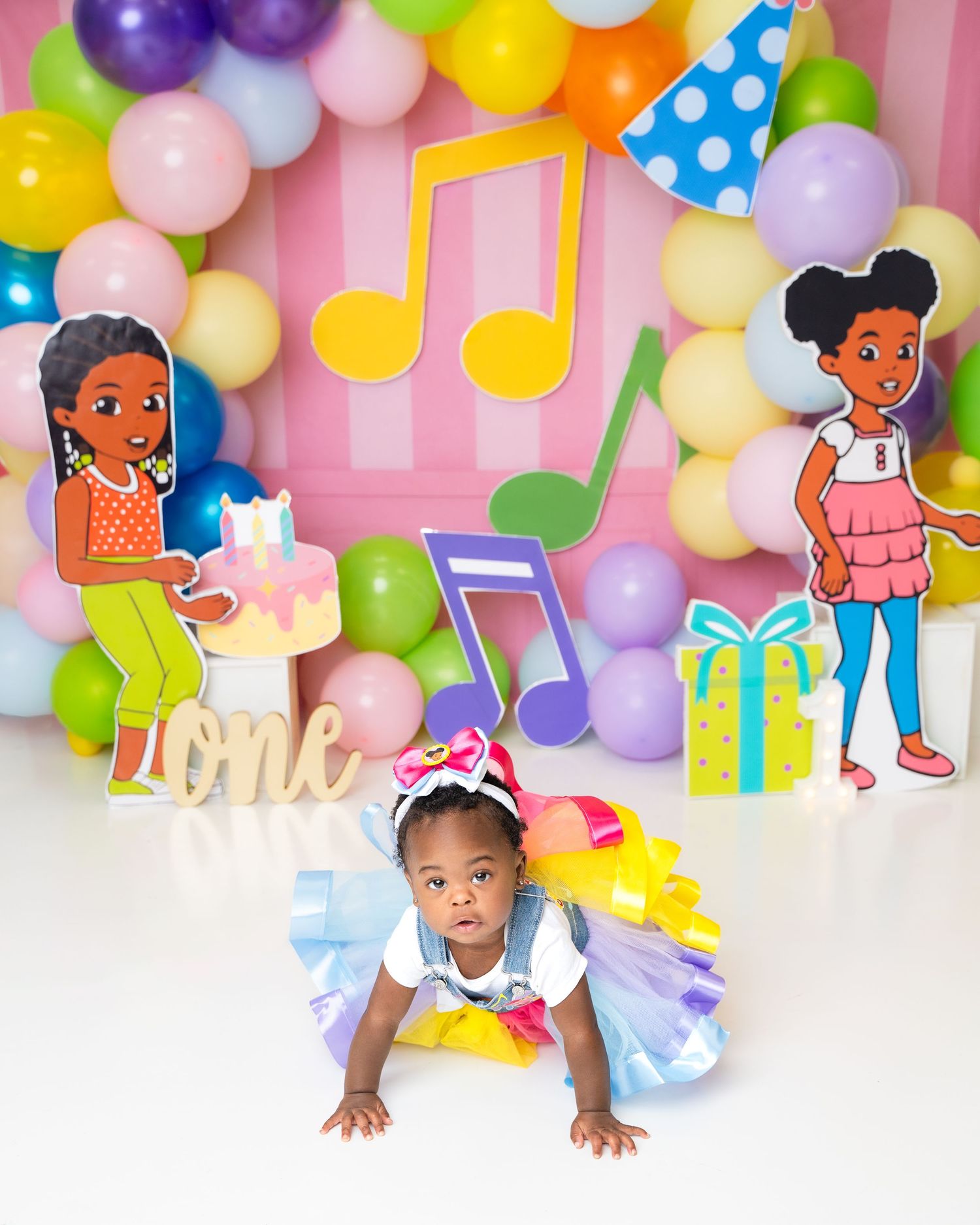 Metro Detroit children photographer photographing a playful toddler in studio Vibrant balloon arch with cartoon character