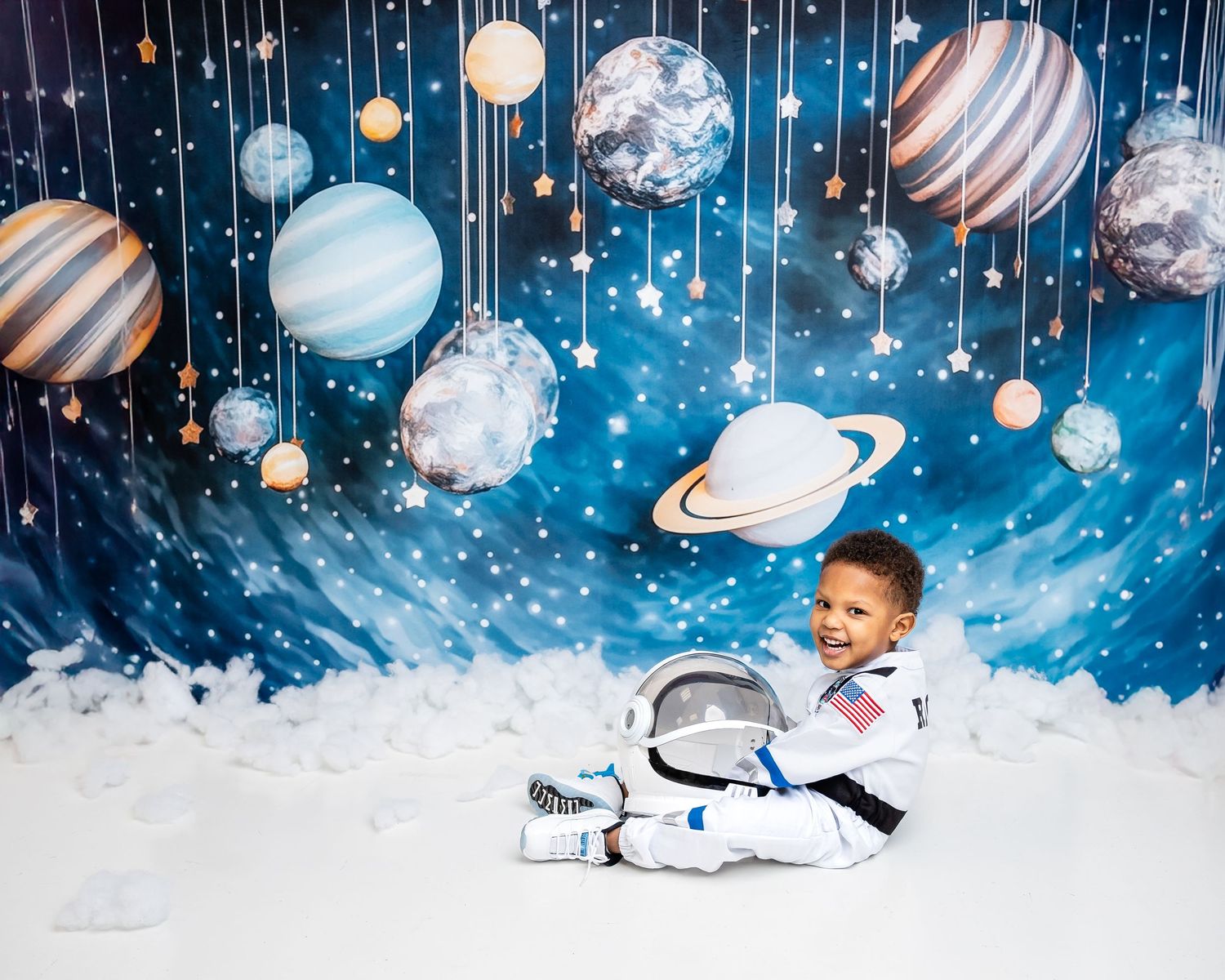 Metro Detroit children photographer  Space-themed photo backdrop with planets, stars, and celestial bodies against a dark blue background.