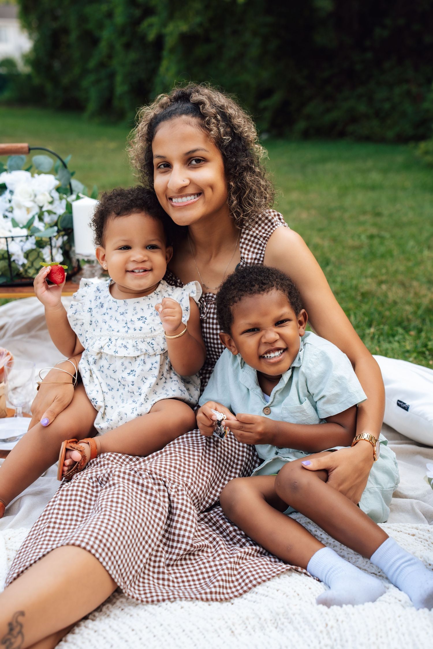 Metro Detroit family photographer capturing  a Family picnic photoshoot on white blanket with gingham and floral dresses.