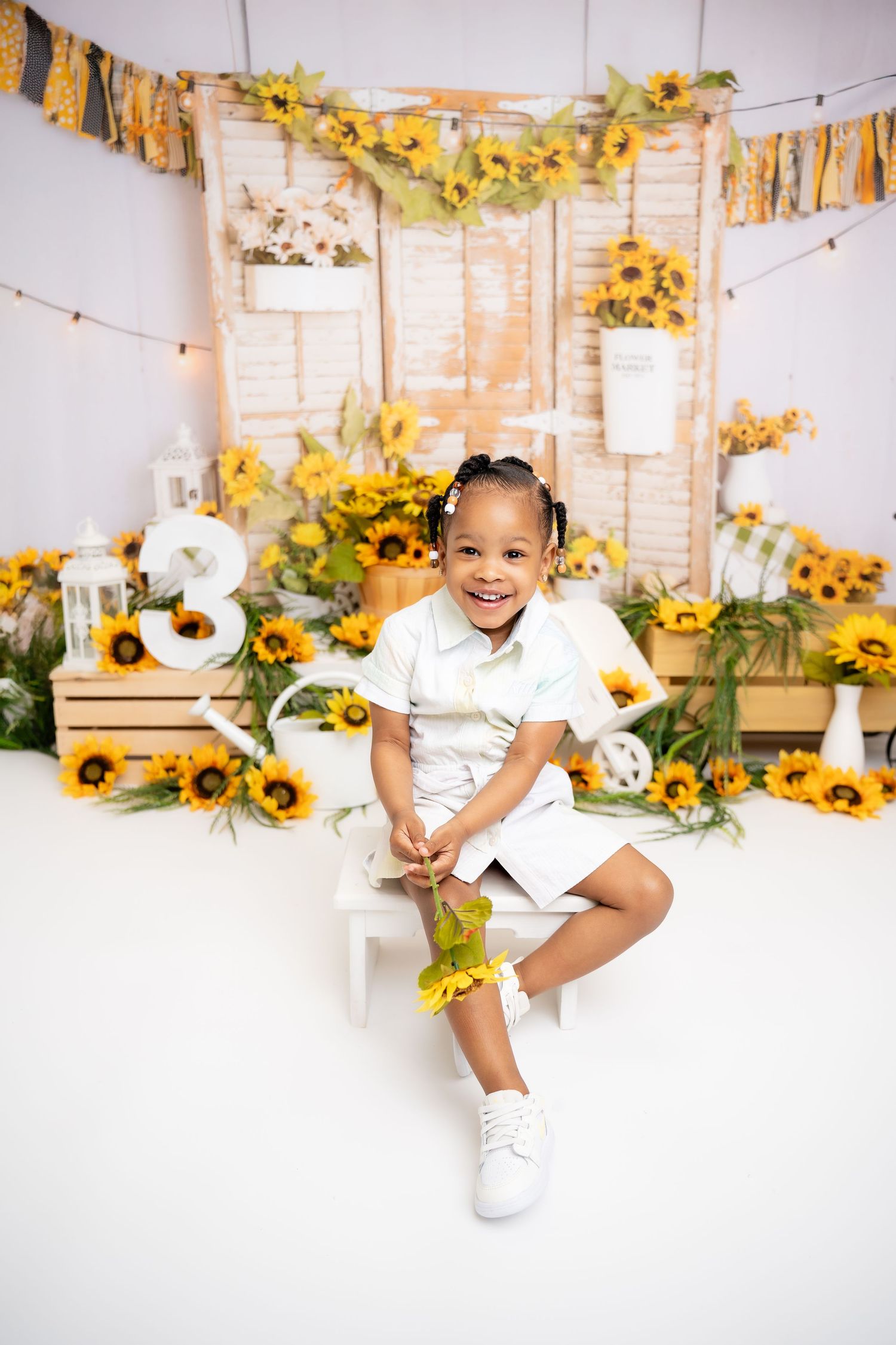 Metro Detroit children photographer Sunflower-themed photoshoot with rustic wooden backdrop and yellow decorations.