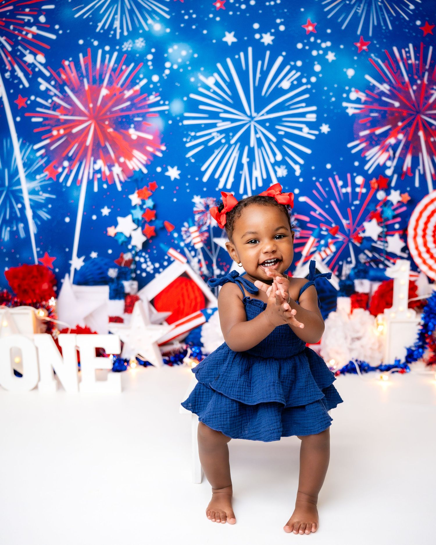 Metro Detroit children photographer Fourth of July themed photo setup with fireworks and stars in red, white, and blue.