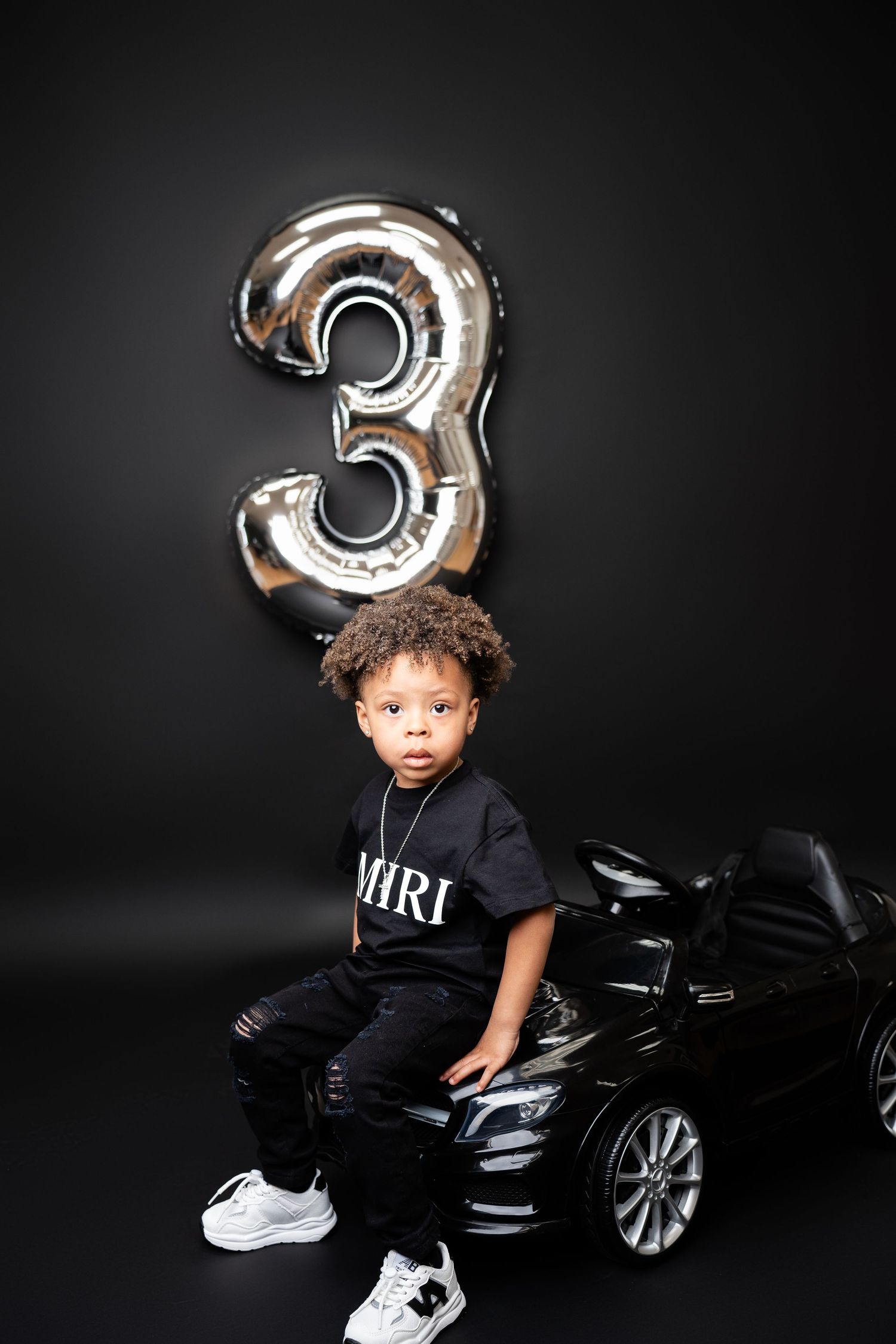 Metro Detroit children photographer photographing a toddler Black and silver themed photo setup with toy car and metallic number balloon.