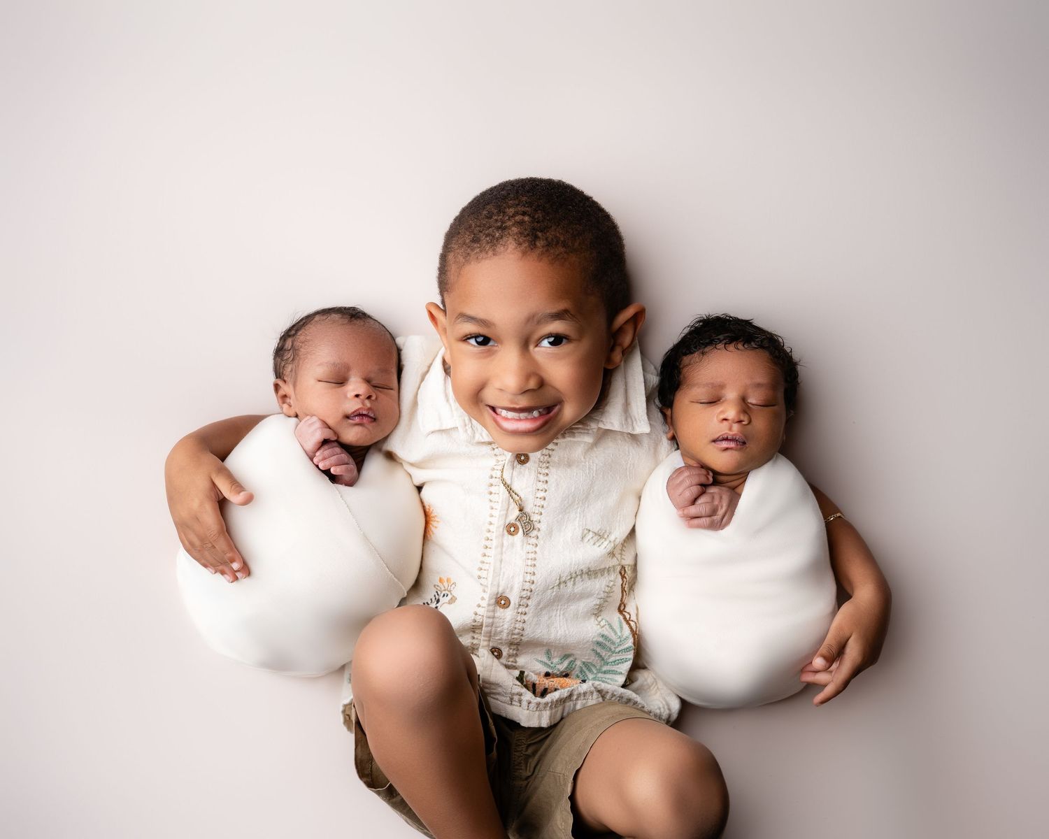 Metro Detroit newborn photographer capturing a peaceful newborn twins with big brother portrait in studio