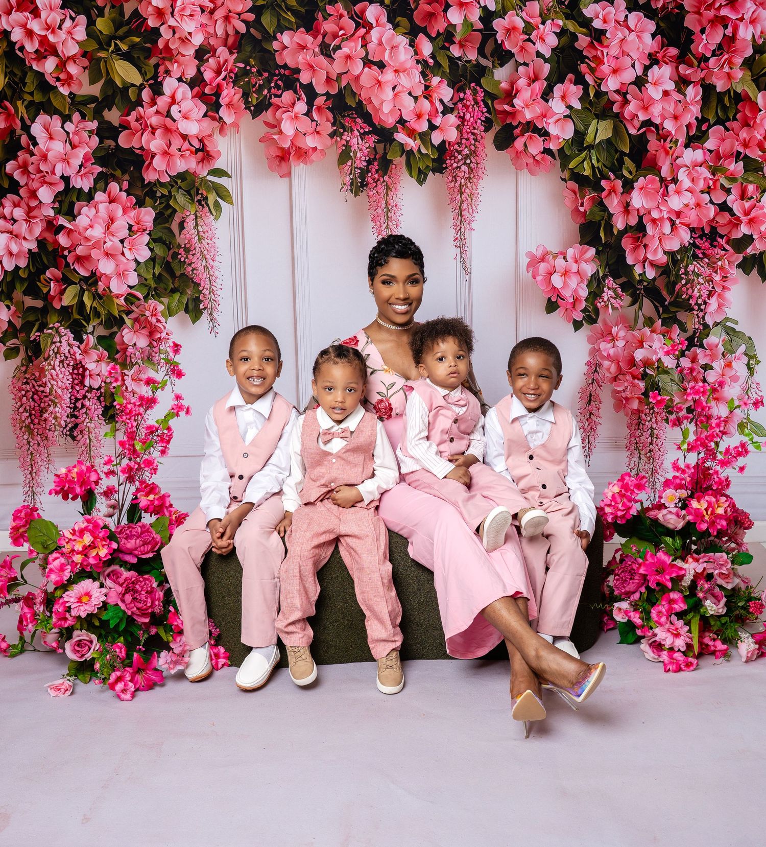 Metro Detroit family photographer capturing Family portrait session with pink floral backdrop featuring coordinated pink and white outfits.