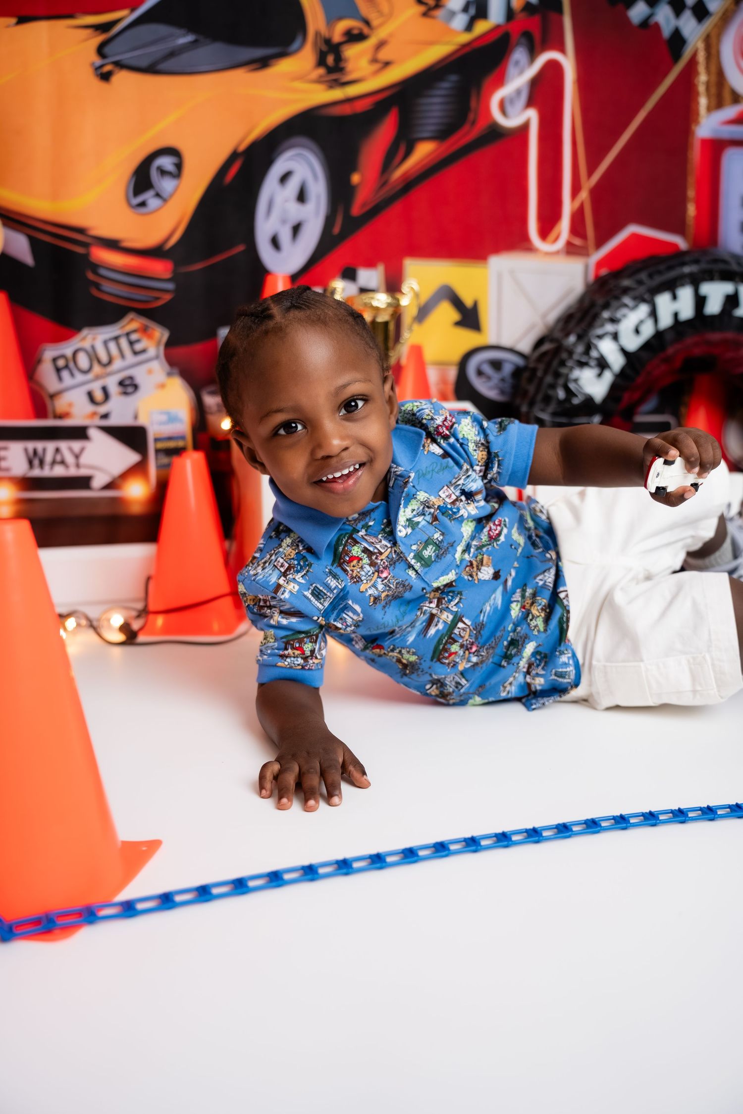 Metro Detroit children photographer Racing-themed photoshoot with blue outfit against red and white backdrop.