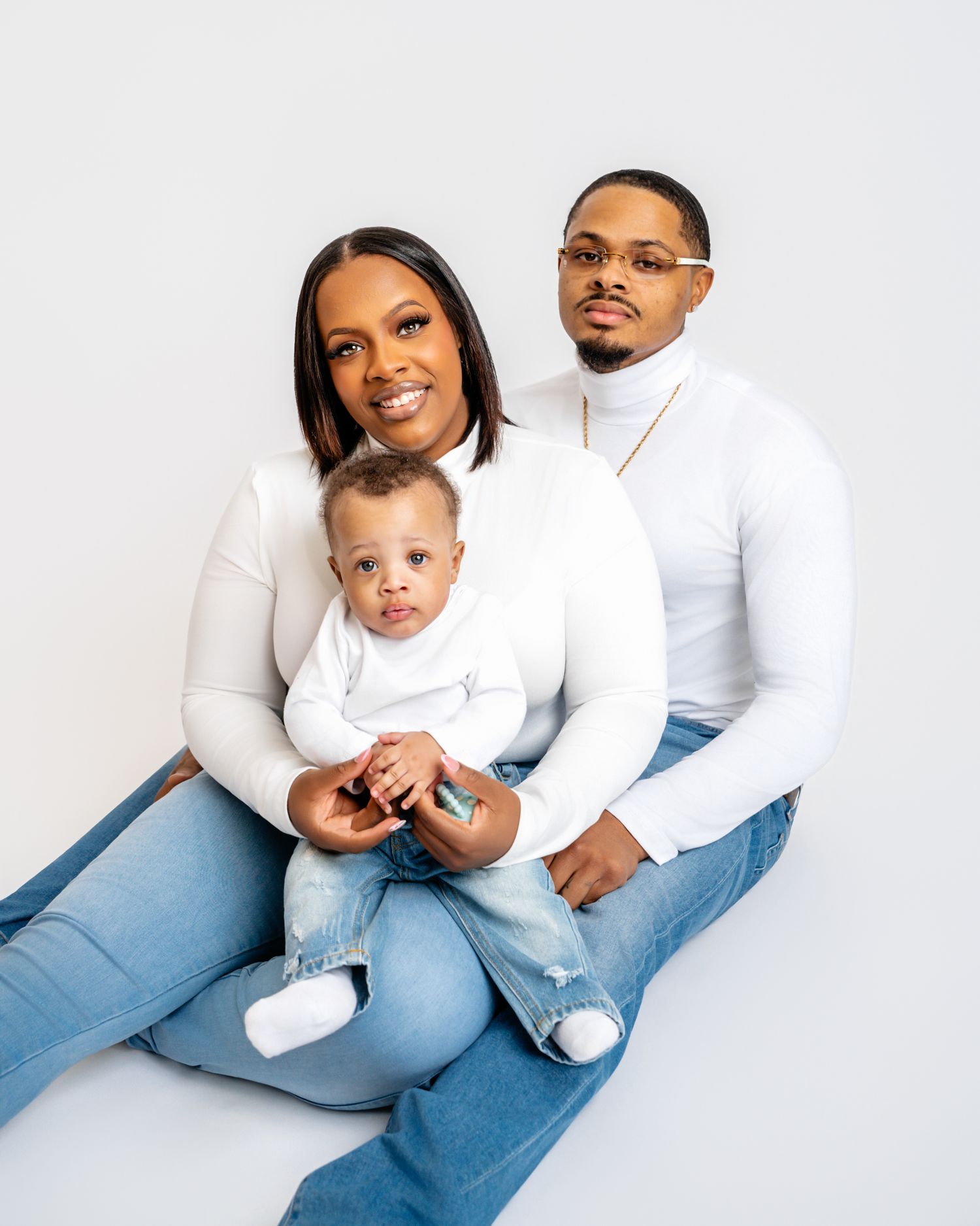 Metro Detroit family photographer capturing A family wearing matching white tops and blue jeans poses together
