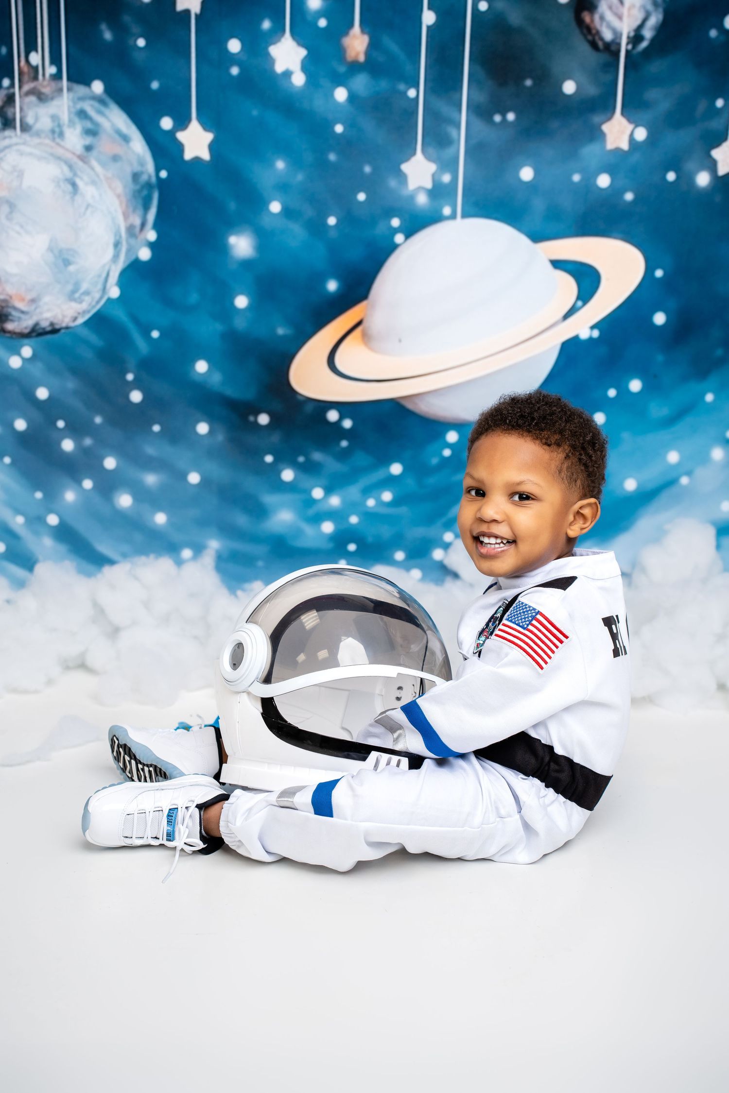 Metro Detroit children photographer  Space-themed photoshoot with astronaut costume against starry blue background.