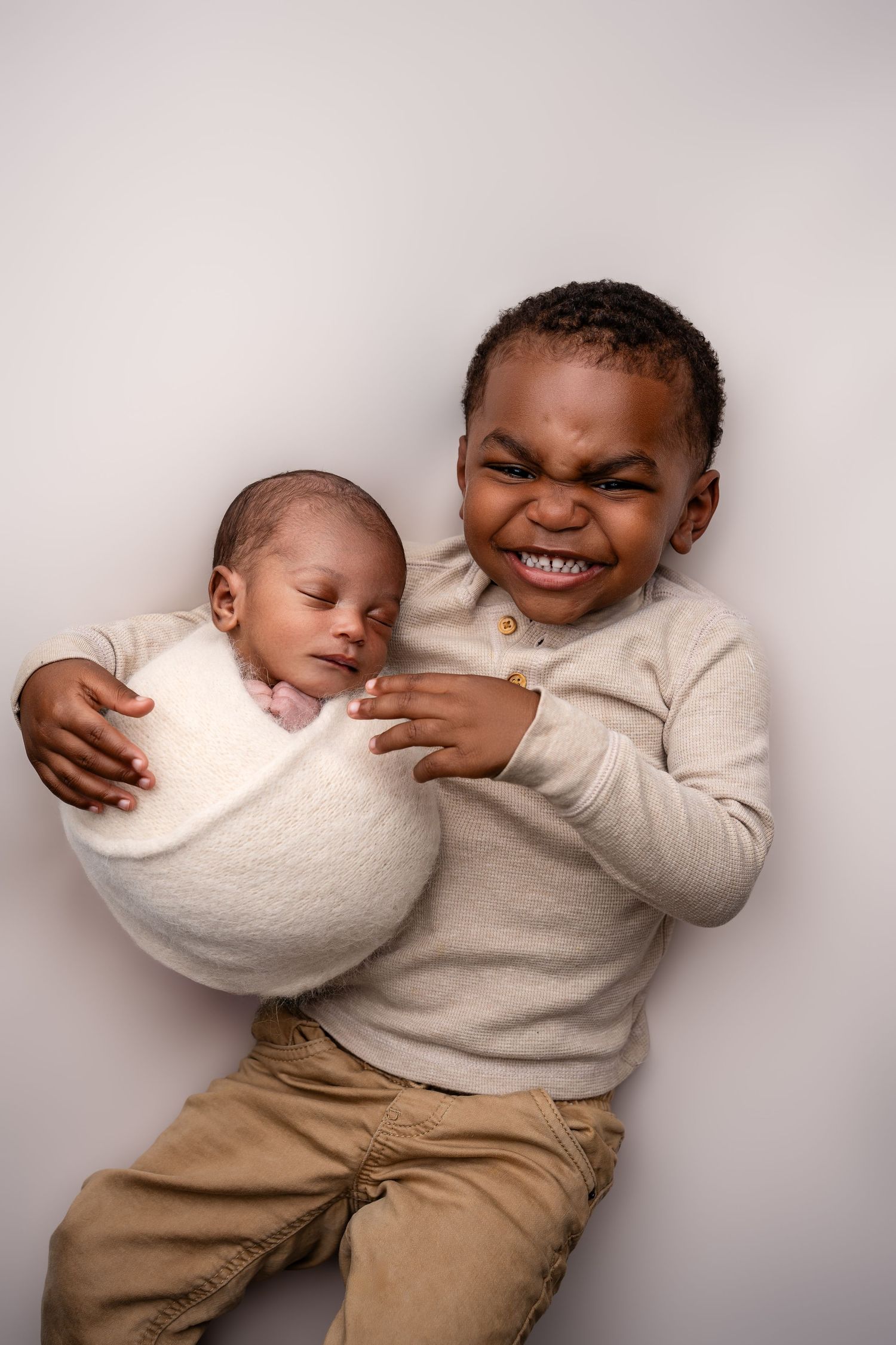 Metro Detroit newborn photographer capturing a peaceful newborn with toddler brother portrait in studio