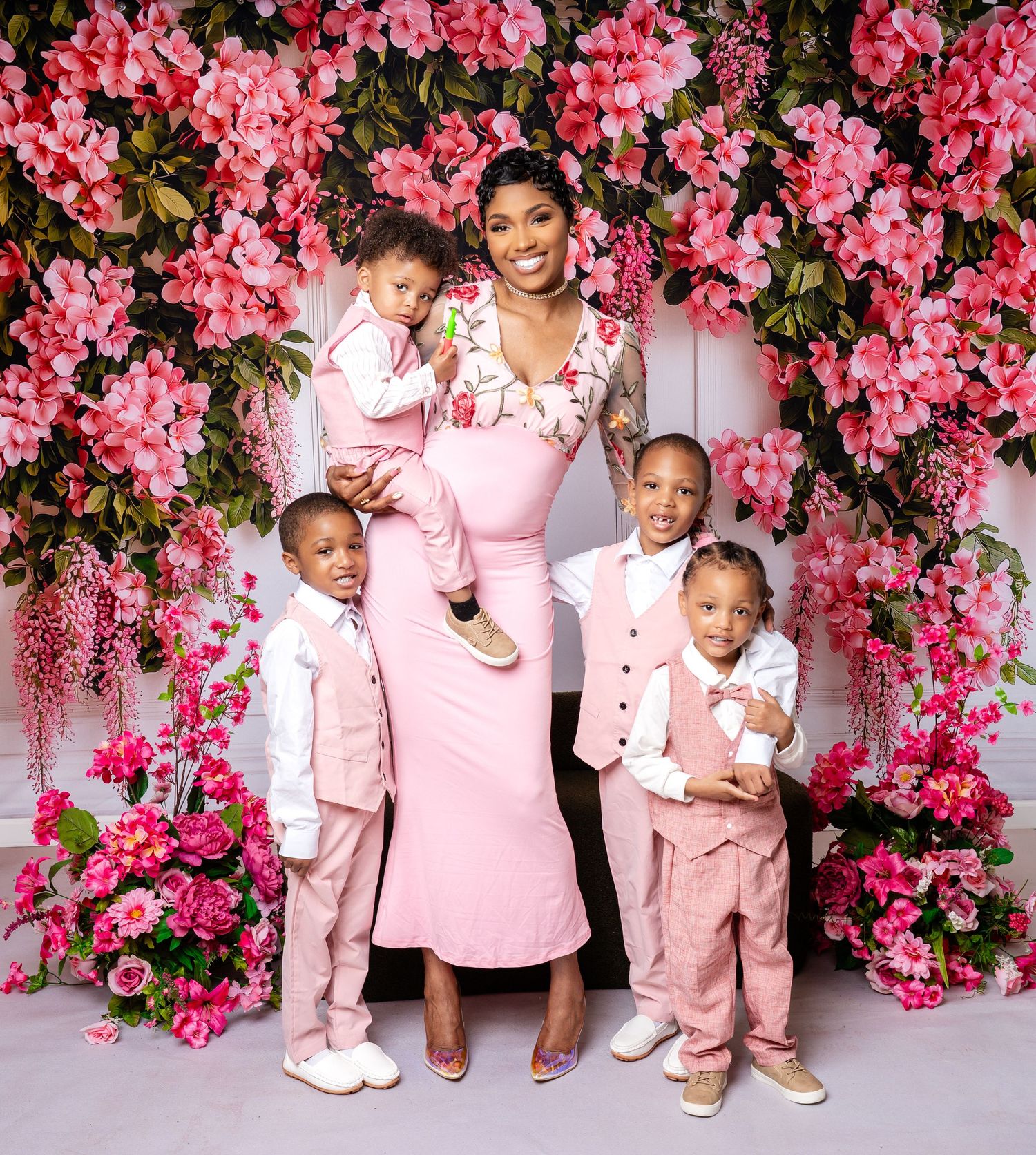 Metro Detroit family photographer capturing family photo with cascading pink flowers backdrop and coordinated pink outfits.