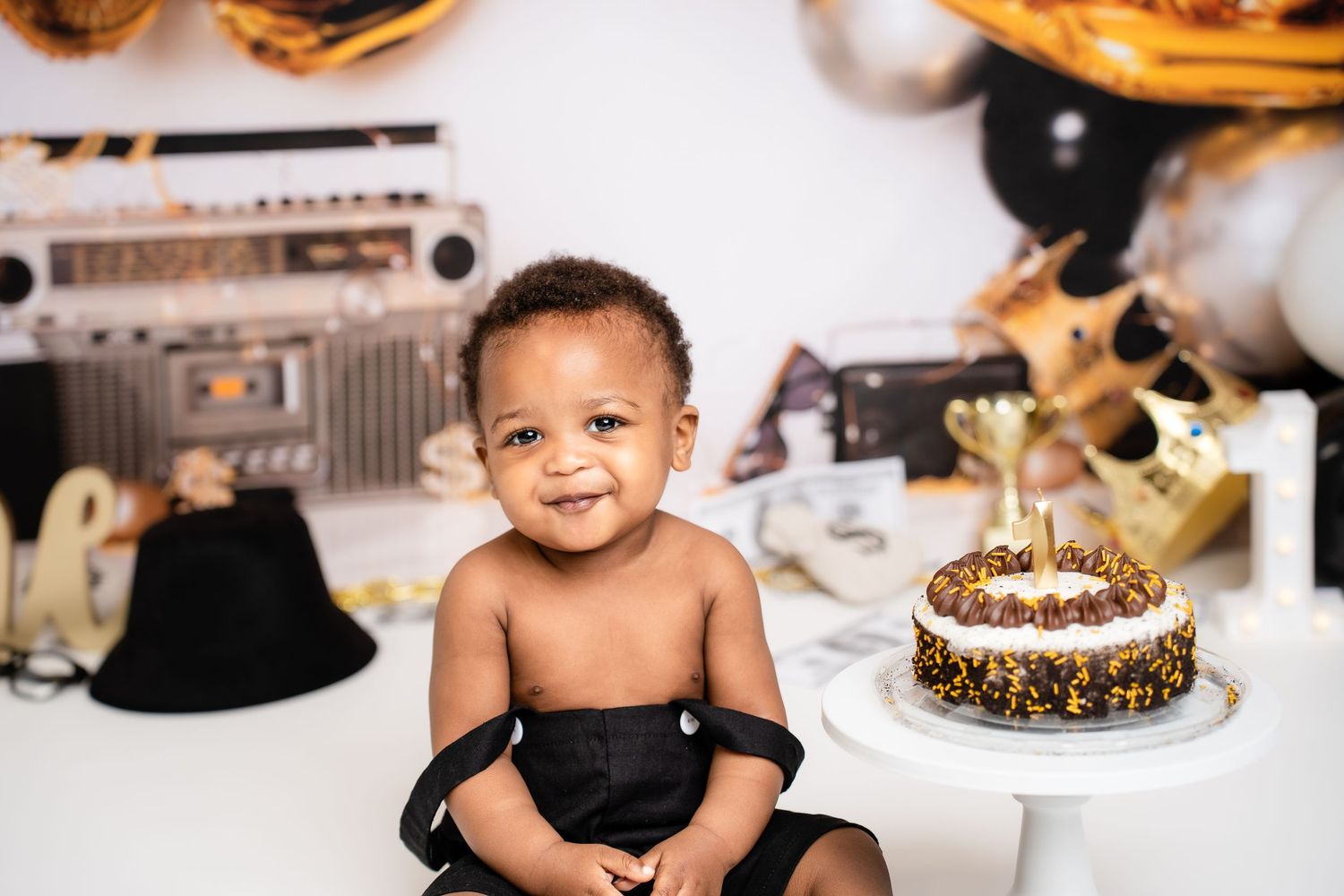 Metro Detroit children photographer Baby cake smash photoshoot with gold and black party decorations.