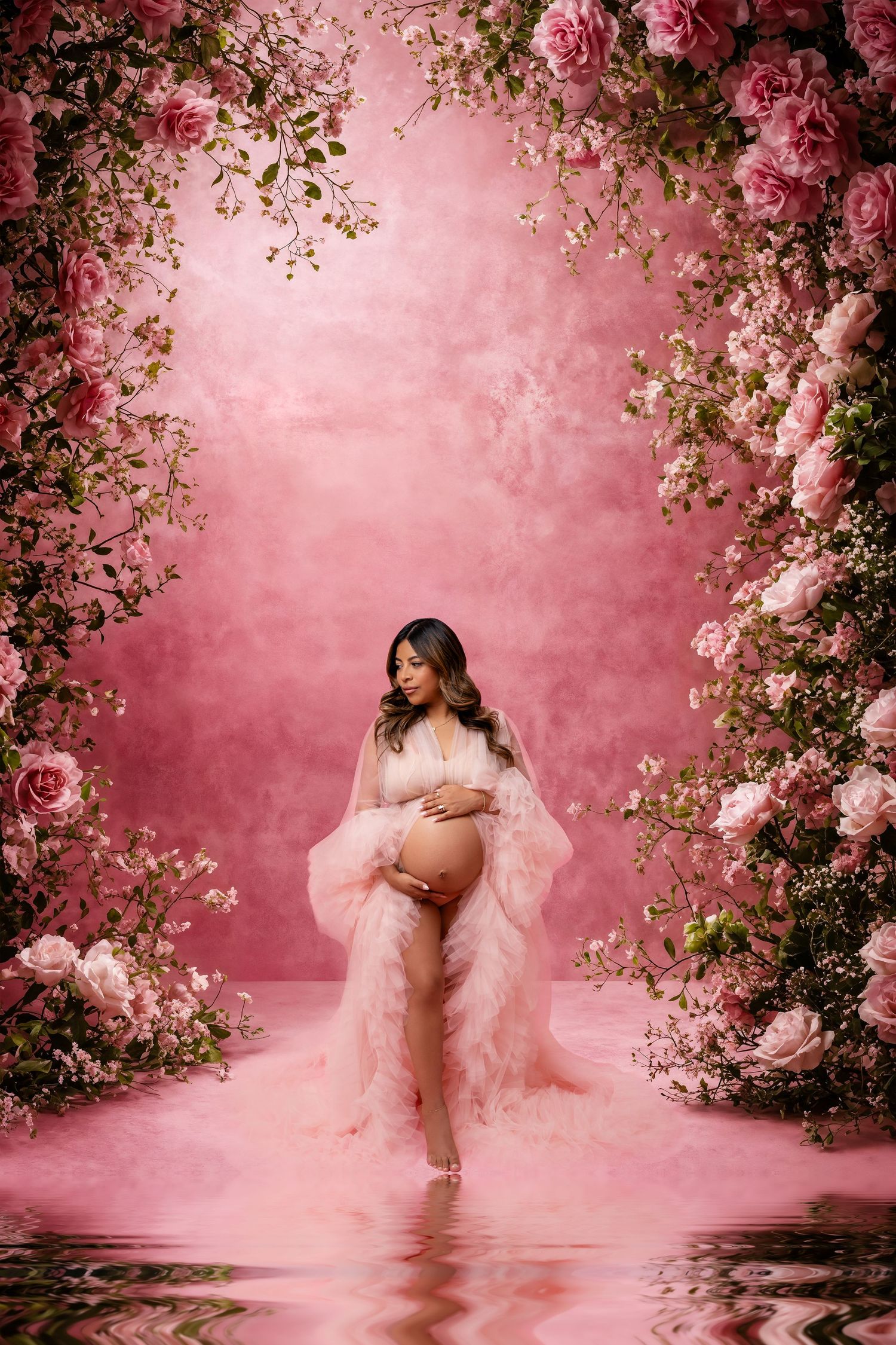 Metro Detroit maternity photographer capturing an expecting mom portrait surrounded by pink roses in romantic garden setting.