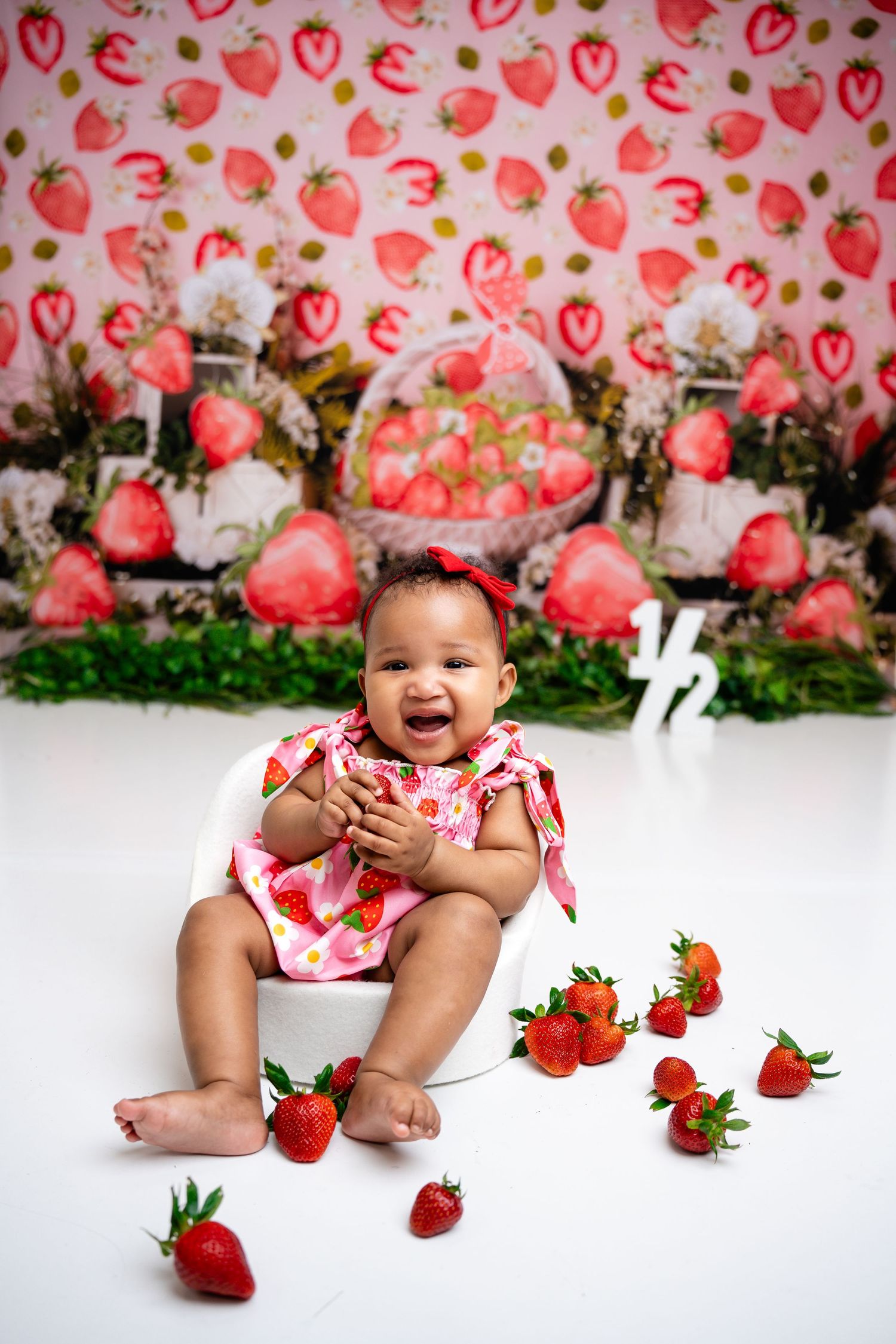 Metro Detroit children photographer Strawberry-themed photoshoot with pink background and fresh strawberries.
