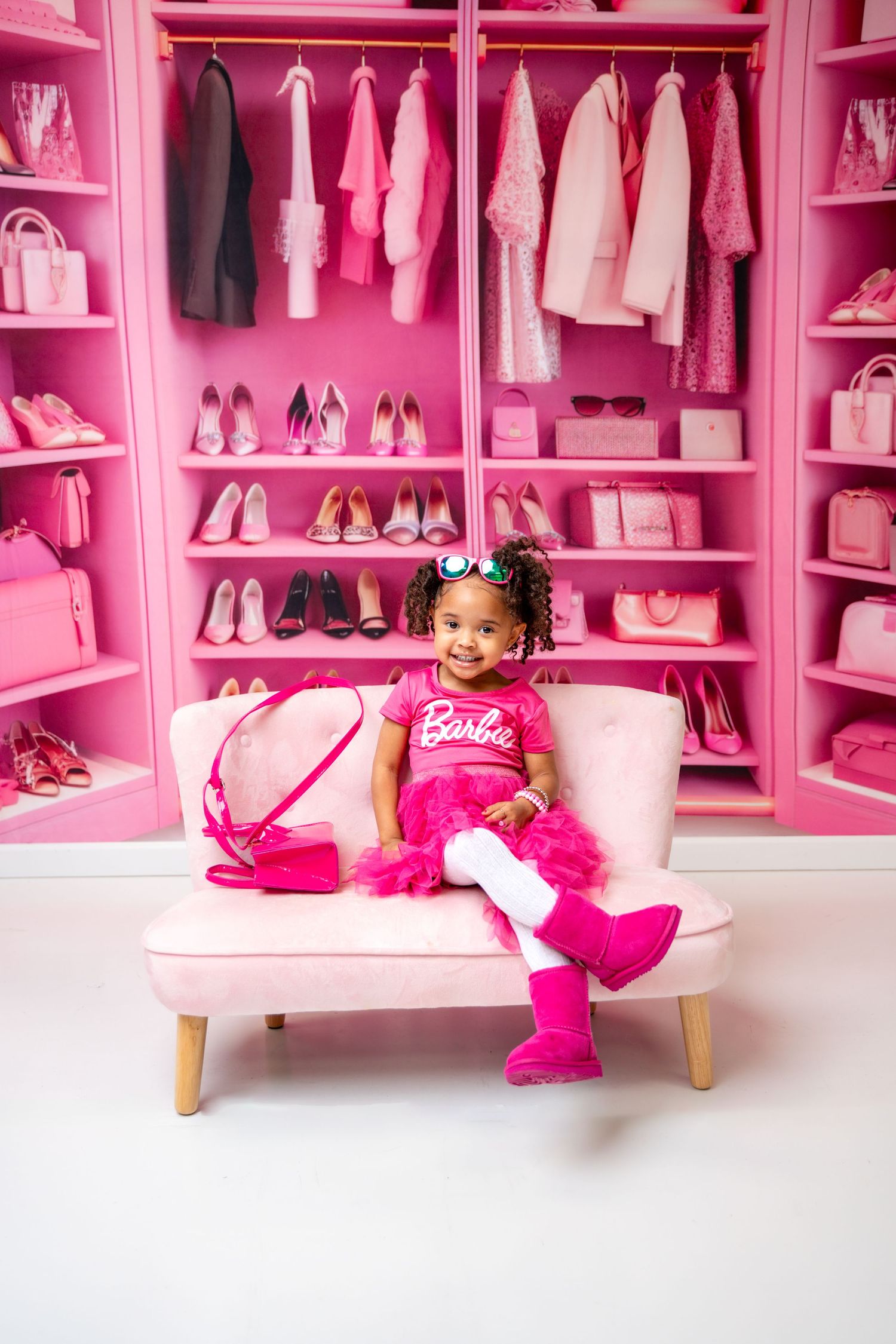 Metro Detroit children photographer photographing a toddler All-pink closet setup with shoes, clothes, and Barbie-themed decor.