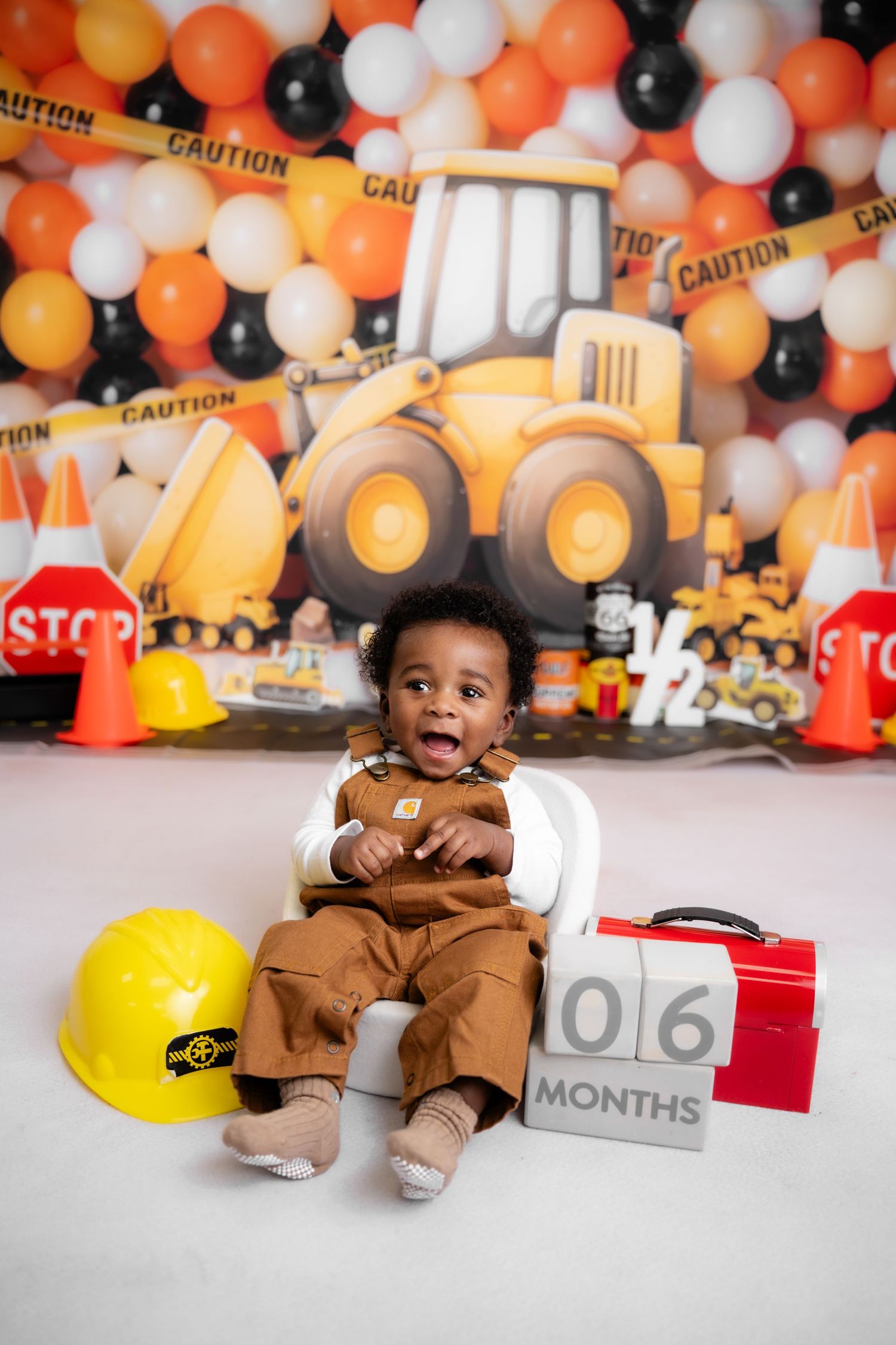 Metro Detroit children photographer Construction themed photo session with orange and black balloons and safety props.