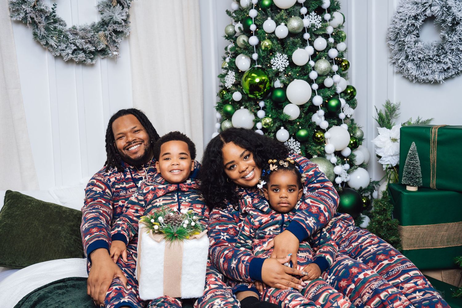 Metro Detroit family photographer capturing a Cozy family moment on white couch with Christmas decorations and wreaths in background.