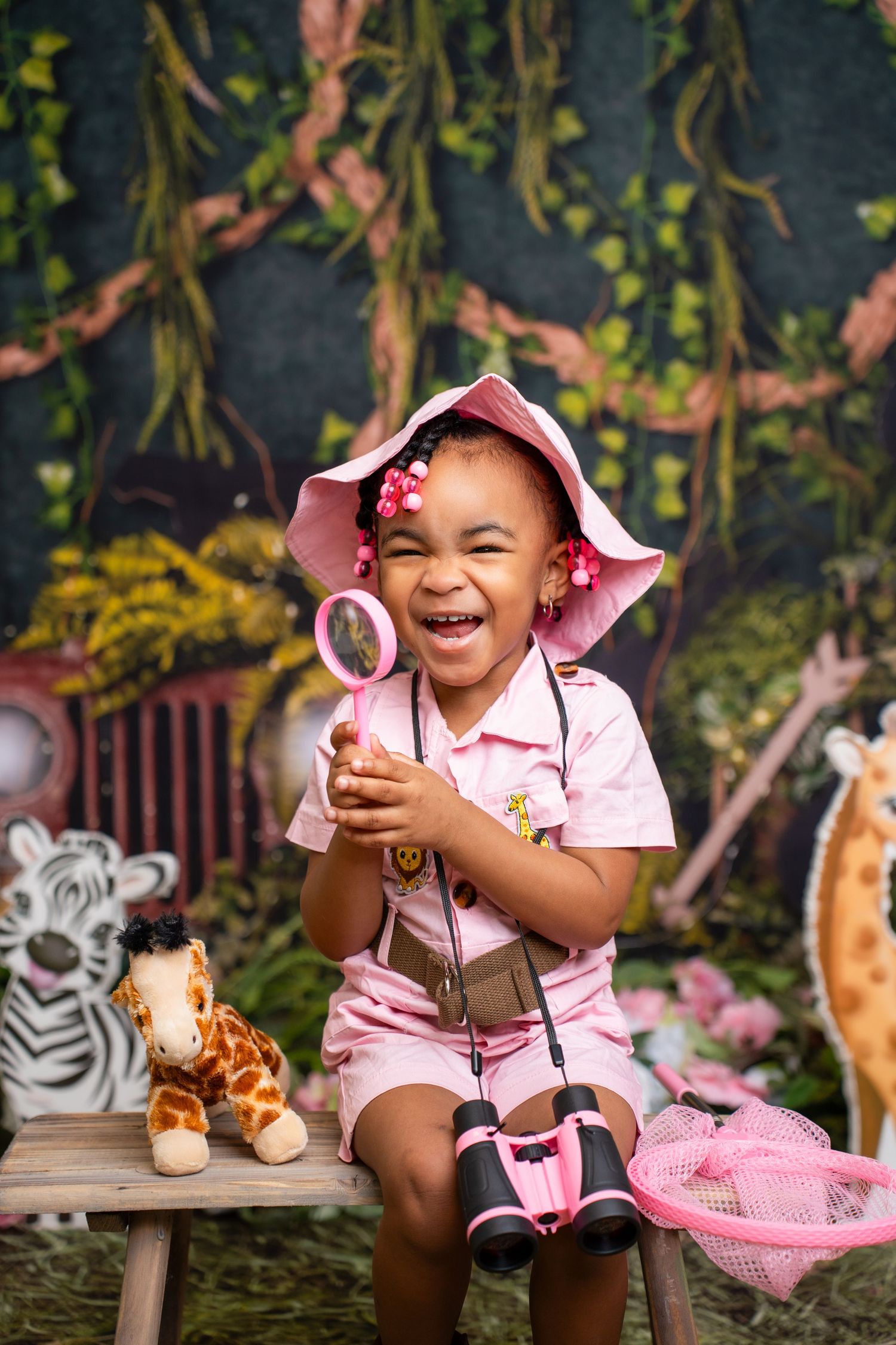 Metro Detroit children photographer photographing a toddler Safari-themed photo set with plush animals, greenery, and natural decor.