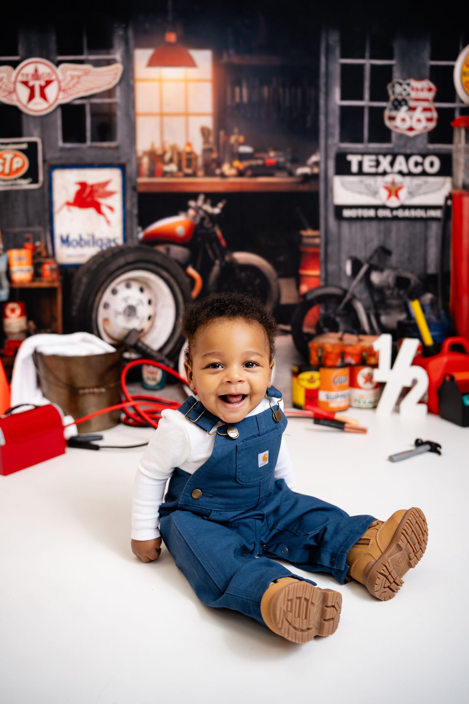 Metro Detroit children photographer photographing a playful toddler in studio with vintage auto shop themed photo setup